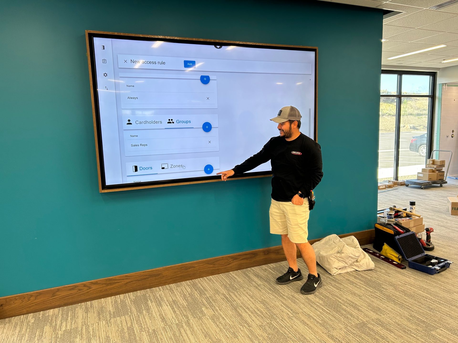 Man pointing at a large screen displaying an access rule interface.