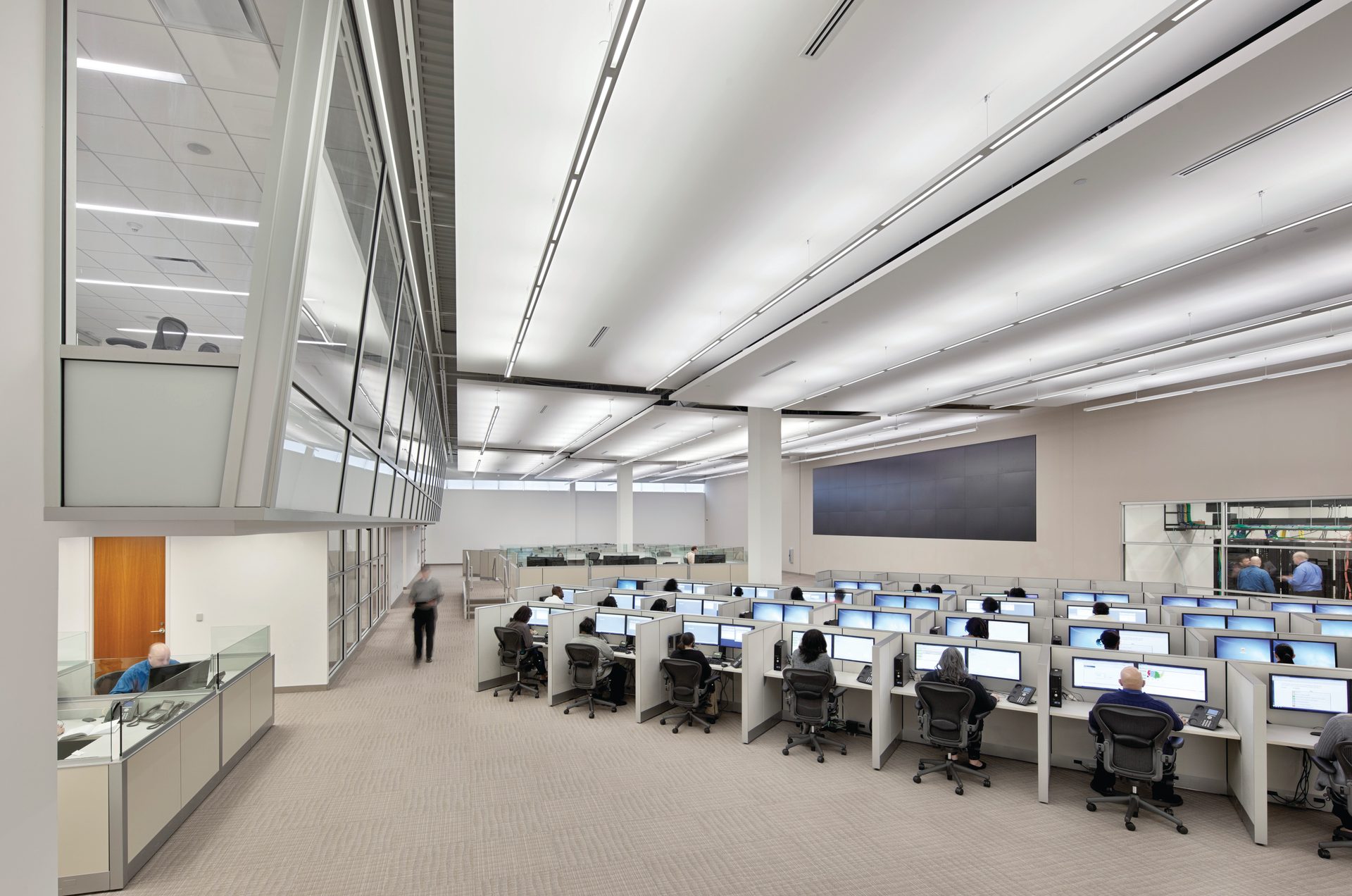 Modern open office with cubicles, computers, and workers.