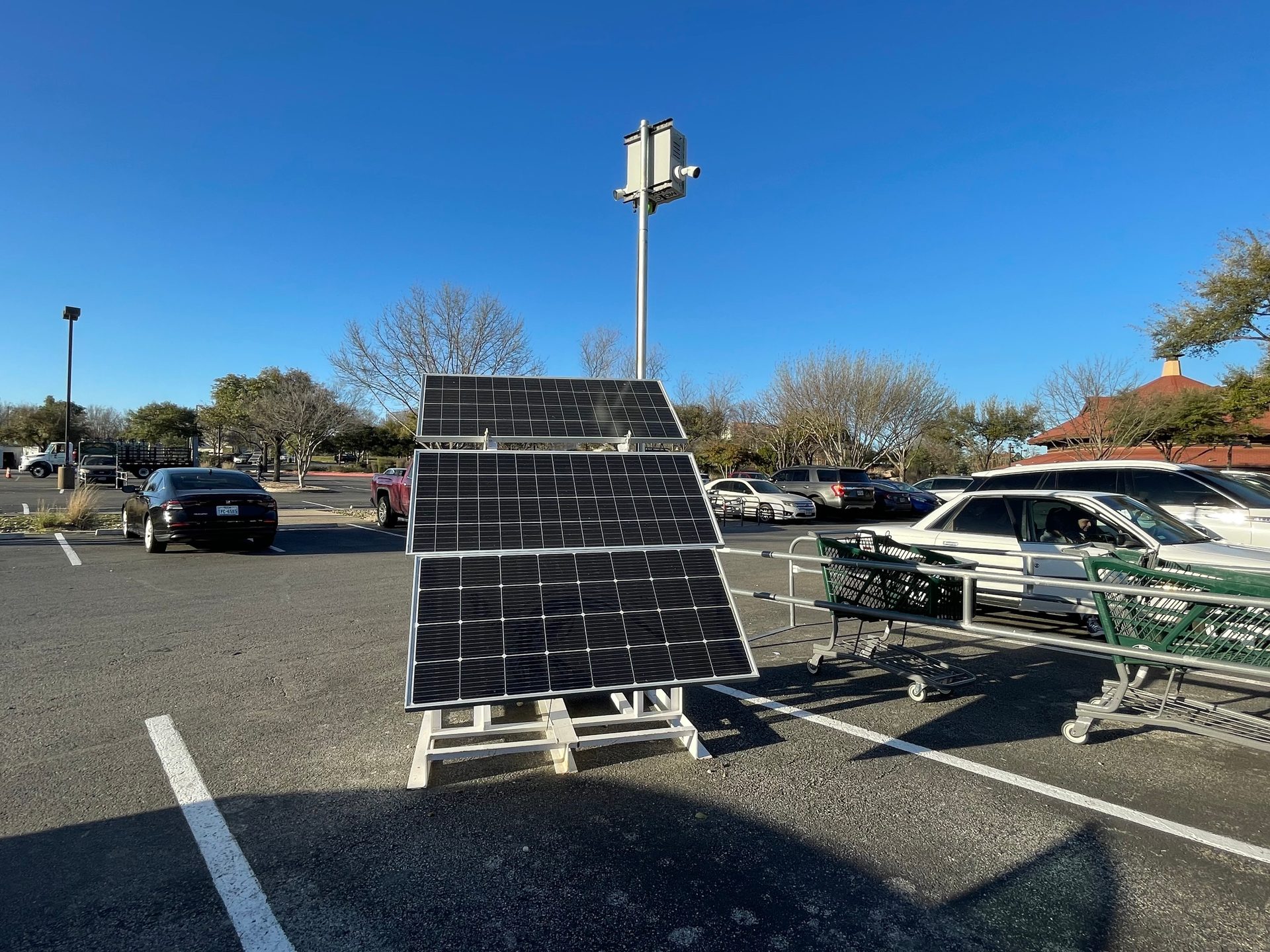 Portable solar panels power a security system in a sunny parking lot.