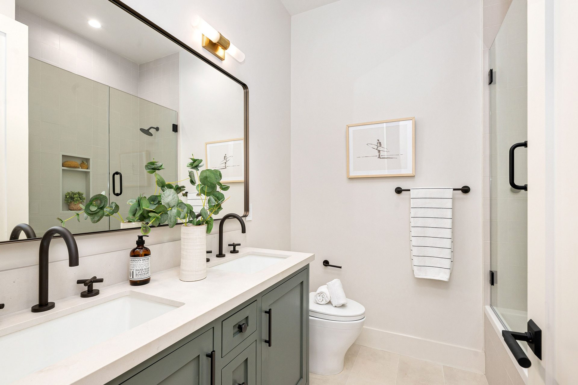 Clean modern bathroom with a green double vanity, mirror, and shower.