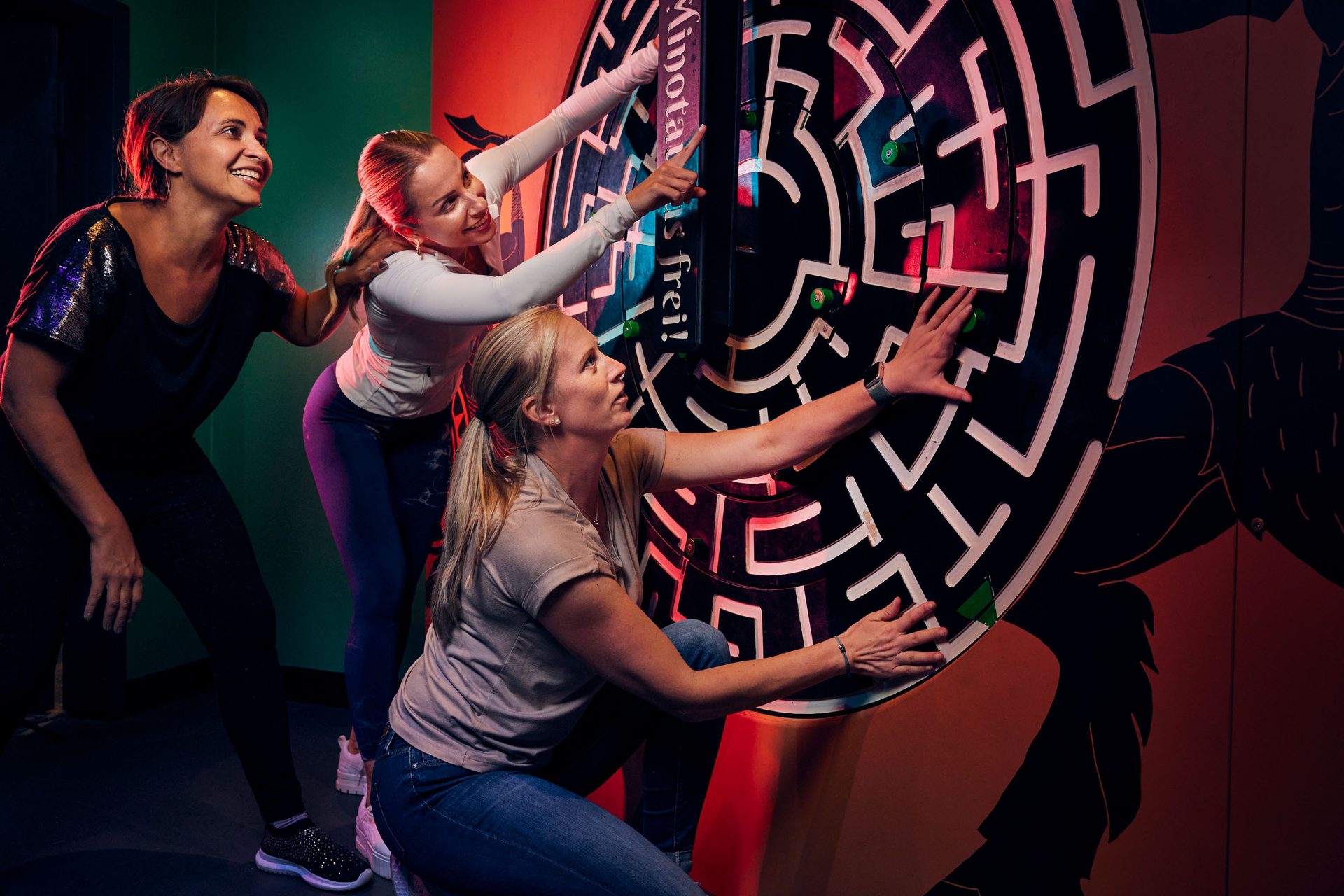 Three women joyfully engaging with an interactive maze game.