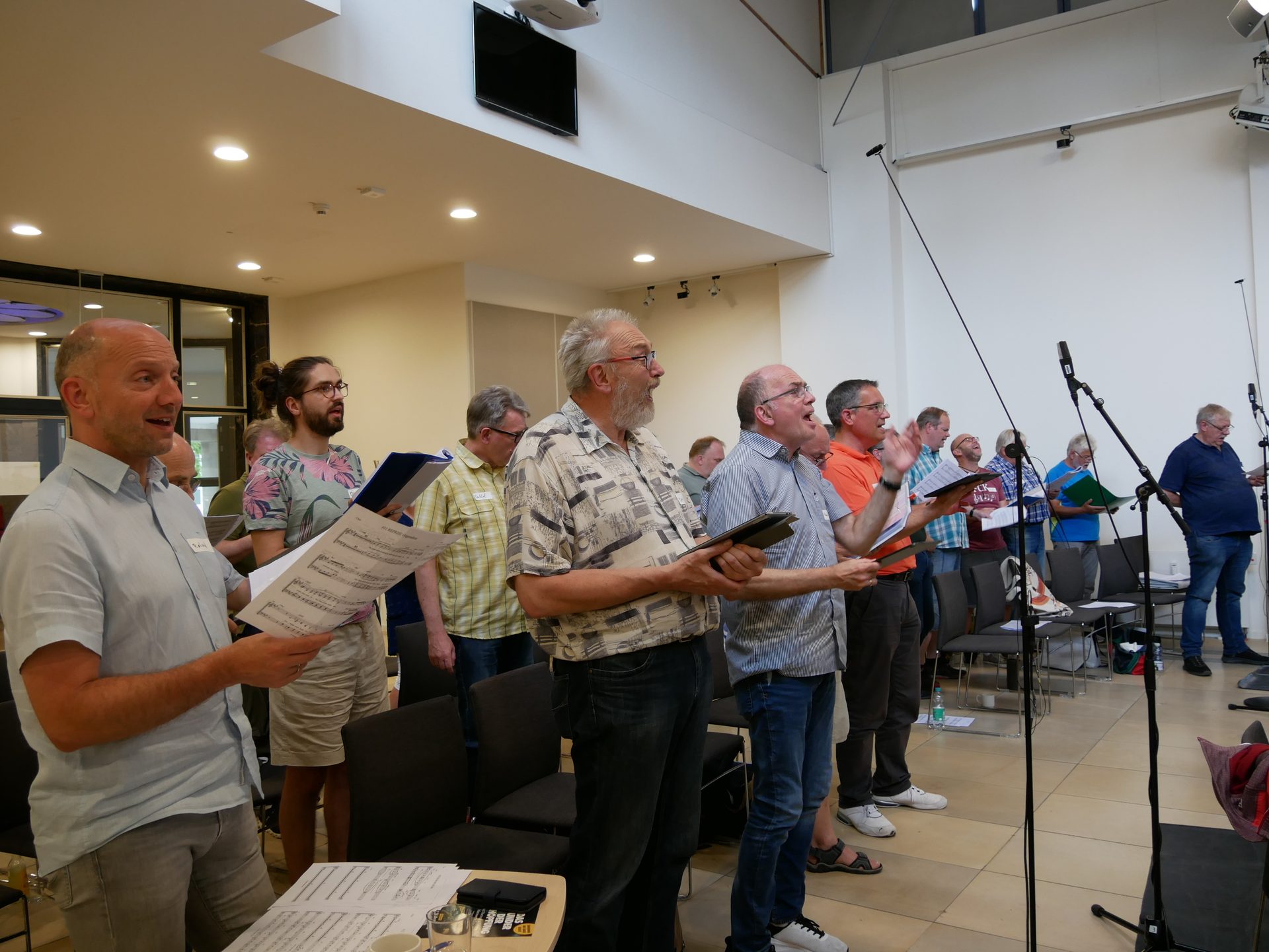 A group of men singing in a choir, holding sheet music.