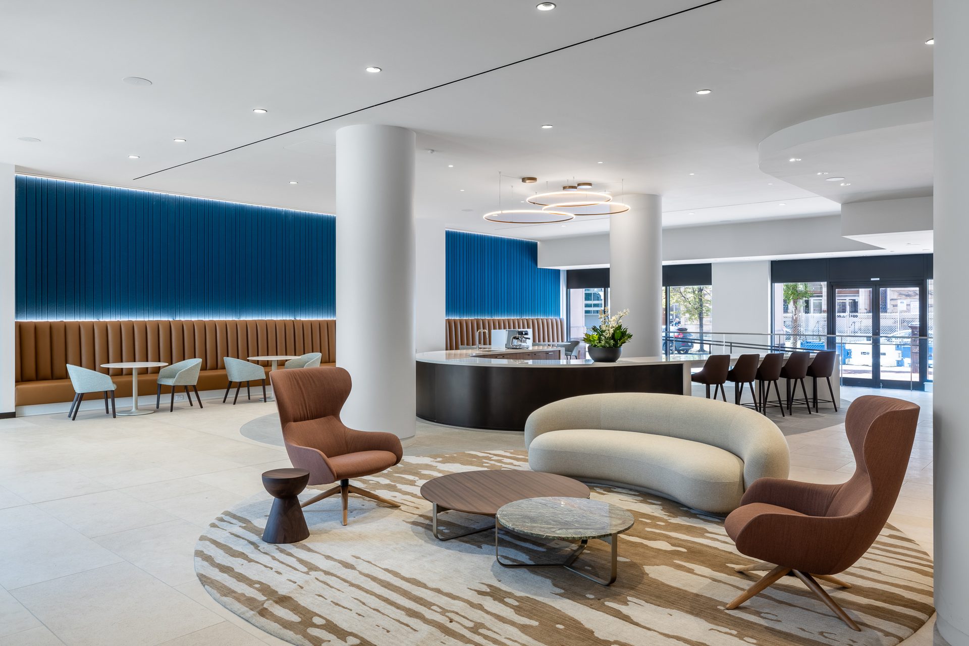 Modern lounge space with diverse seating, a curved counter, and a distinctive blue accent wall.