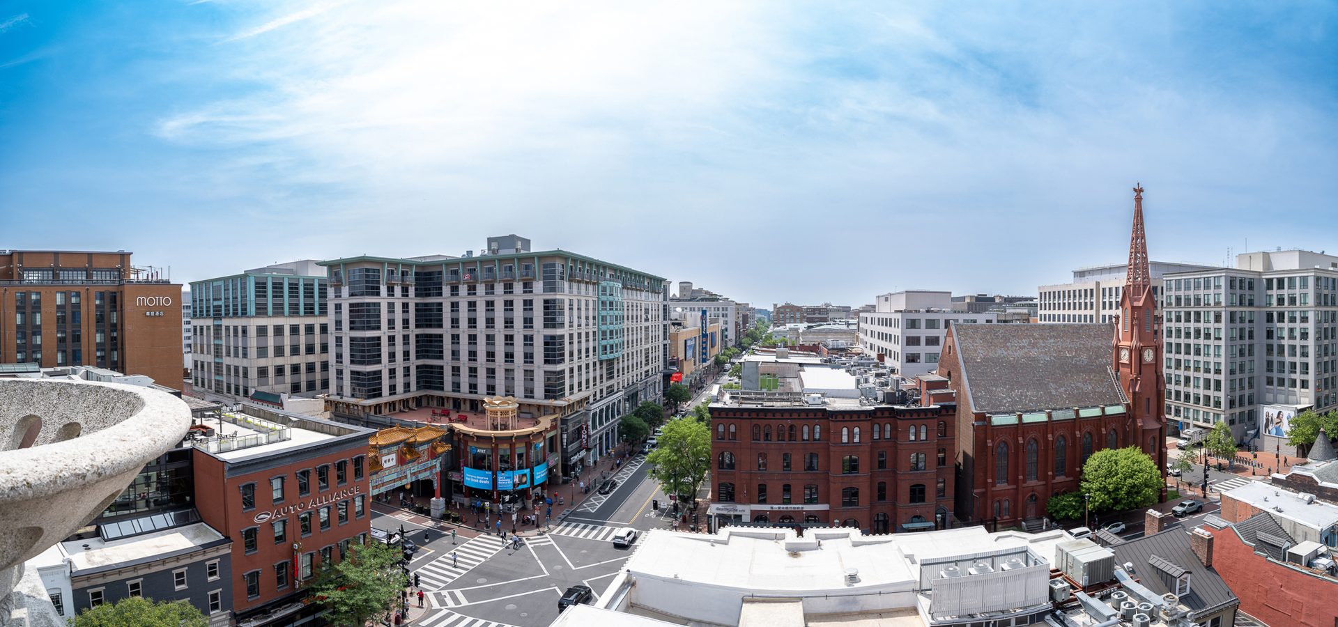 Panoramic view of Washington D.C.'s Chinatown, showing a street, diverse buildings, and a church spire.