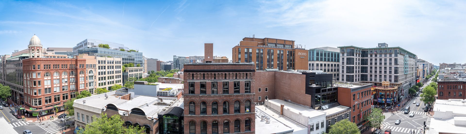 Panoramic cityscape with diverse buildings, streets, and blue sky.