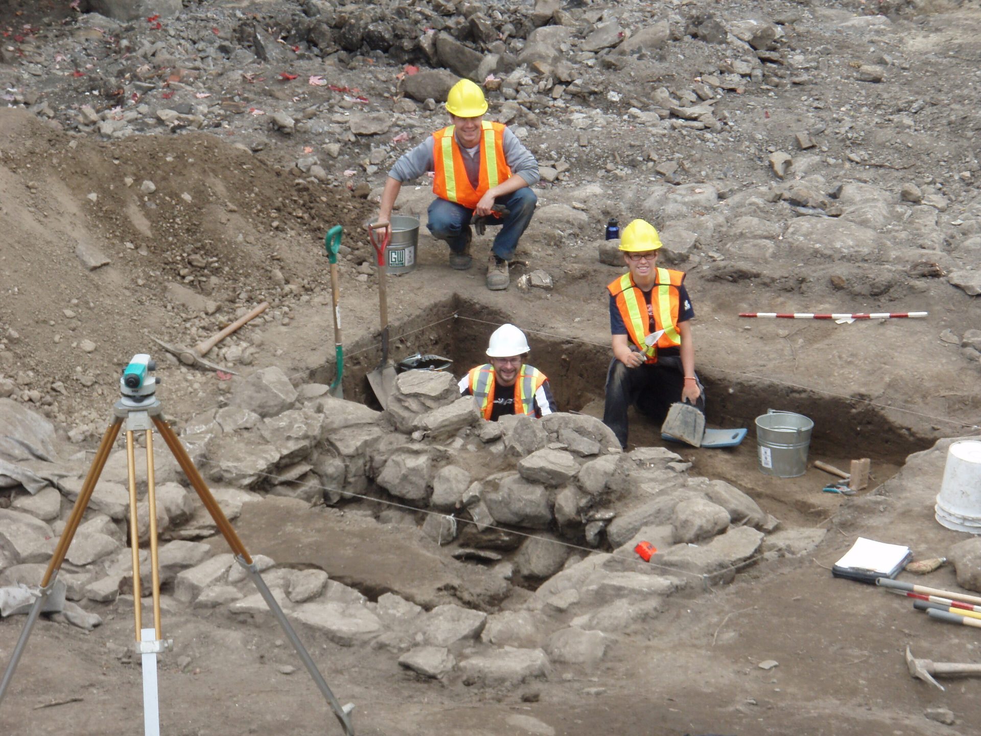 Hard hat, Theodolite, Tradesman, Tripod, Workwear, Slope, Asphalt, Helmet, Bedrock