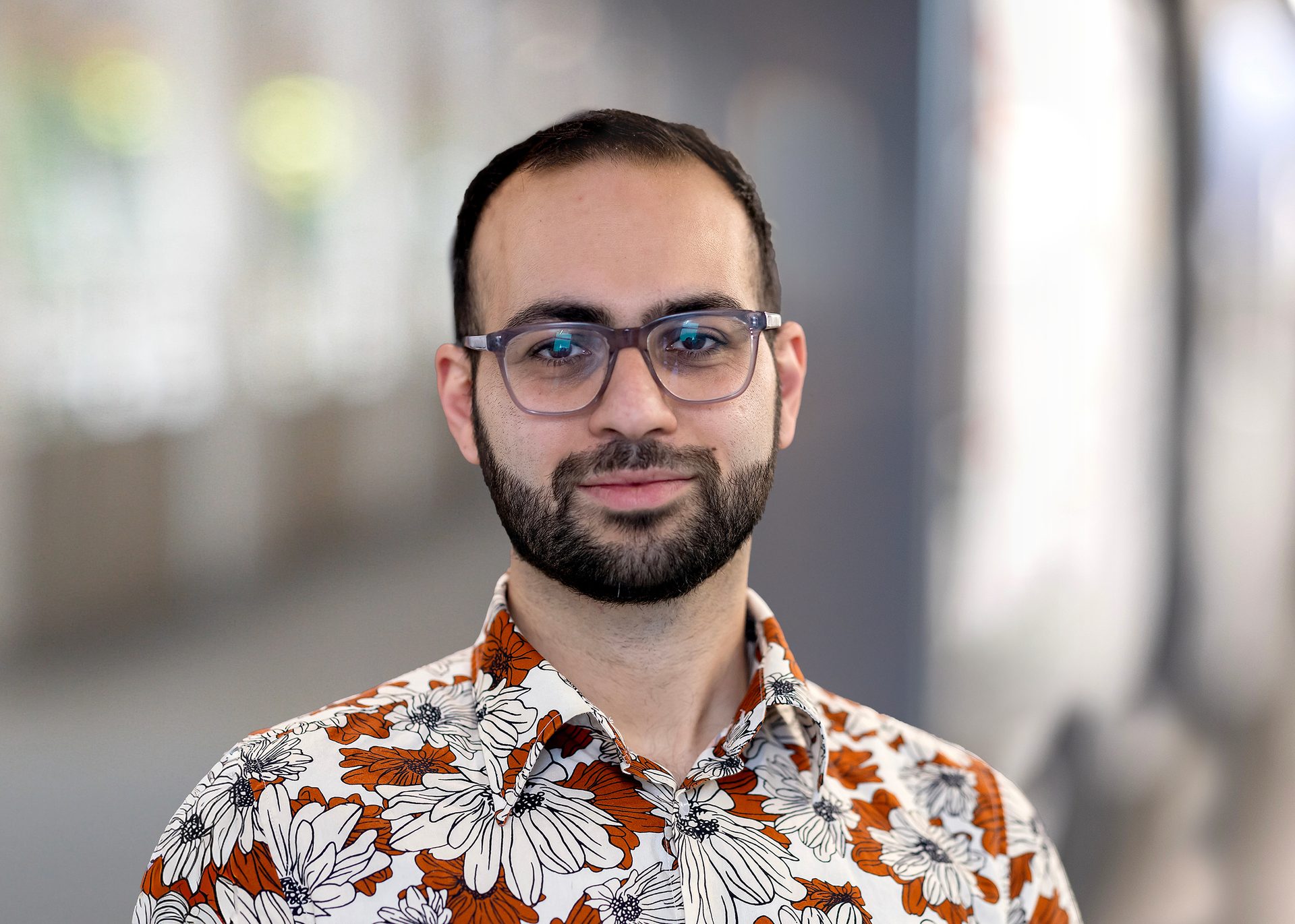 A young male professor wears glasses and floral shirt in science lab
