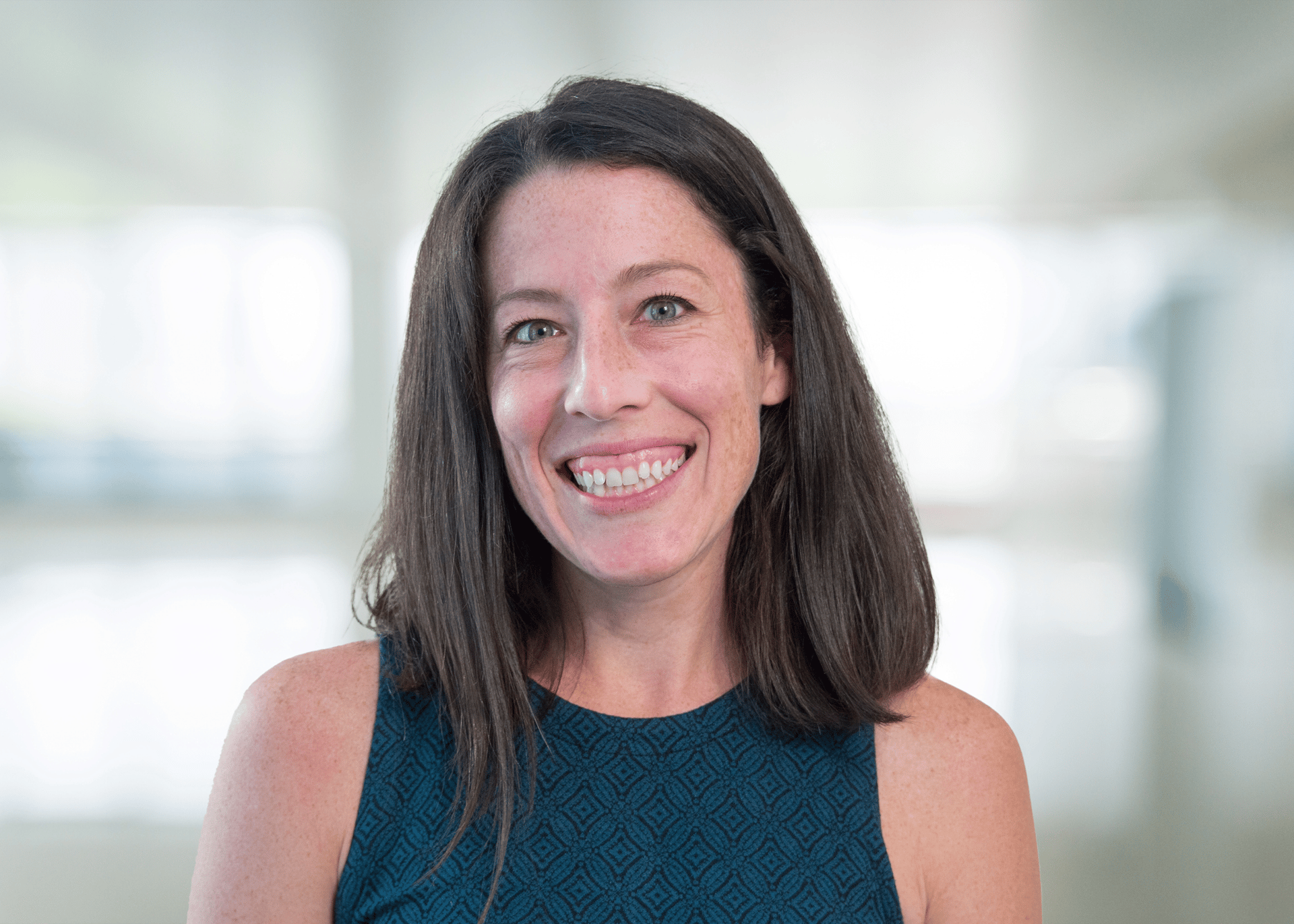 White female professor with dark brown hair and blue eyes wears teal tank top