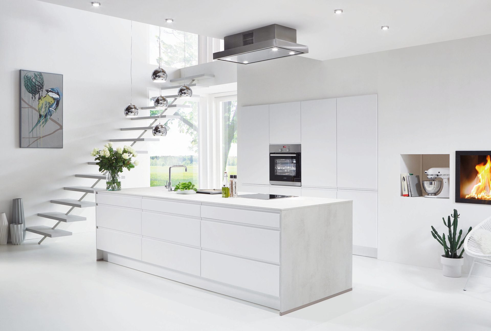 Minimalist white kitchen with island, floating stairs, integrated oven, and a fireplace.