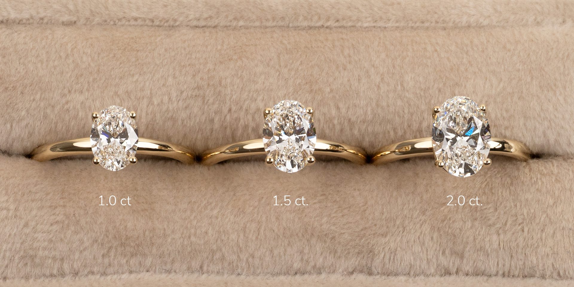 Oval diamond engagement rings in 1.0, 1.5, and 2.0 carat sizes, set on gold bands.
