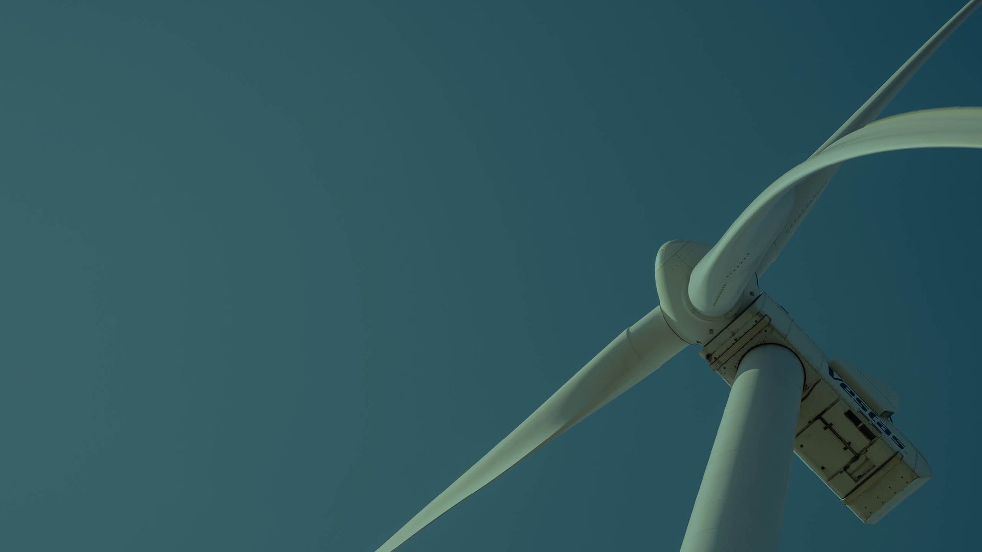 Close-up of a white wind turbine against a clear blue sky, symbolizing renewable energy.