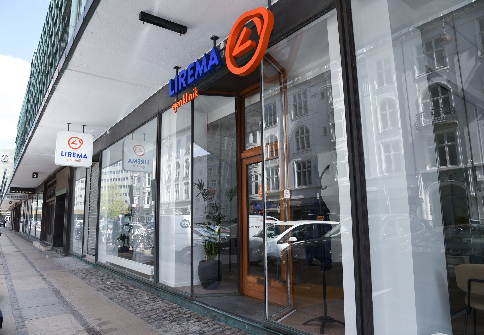 Storefront of LIREMA eye clinic on a city street with reflective windows.