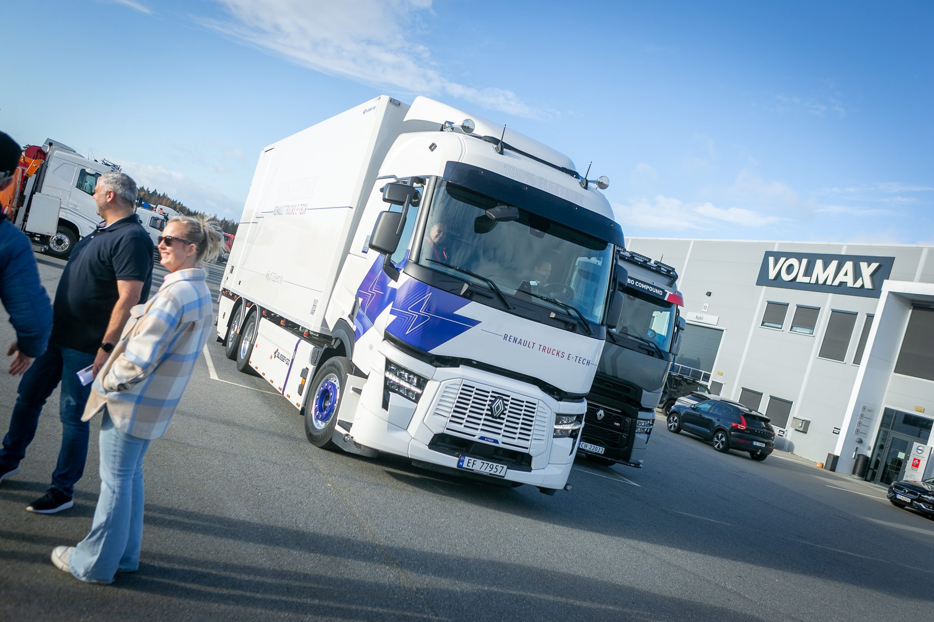 A white Renault E-Tech 100% electric truck, with people and a VOLMAX building in the background.