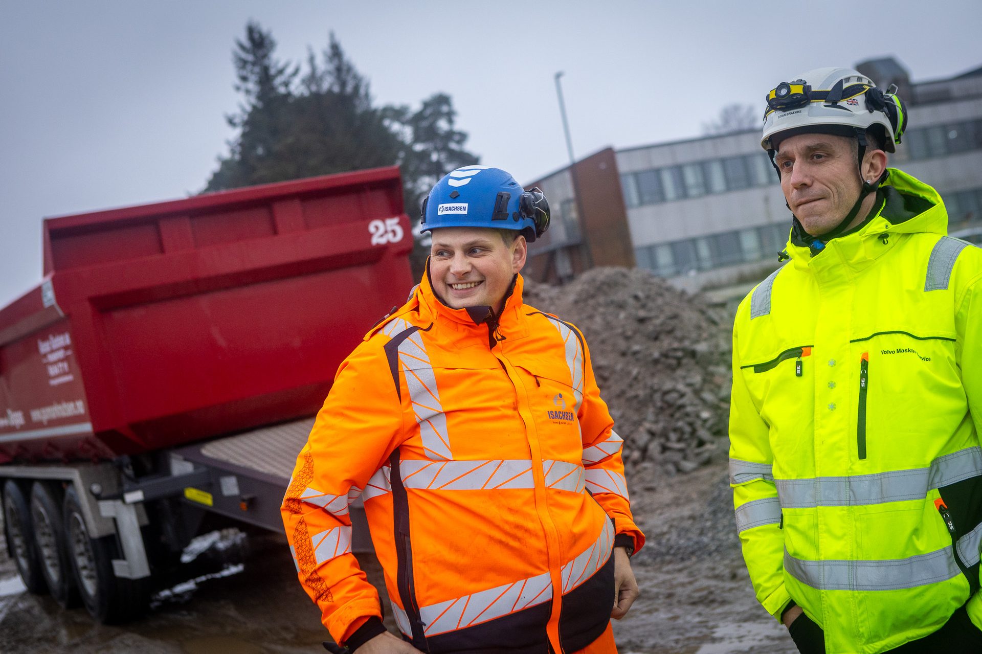 Two men in safety gear and hard hats on a construction site.