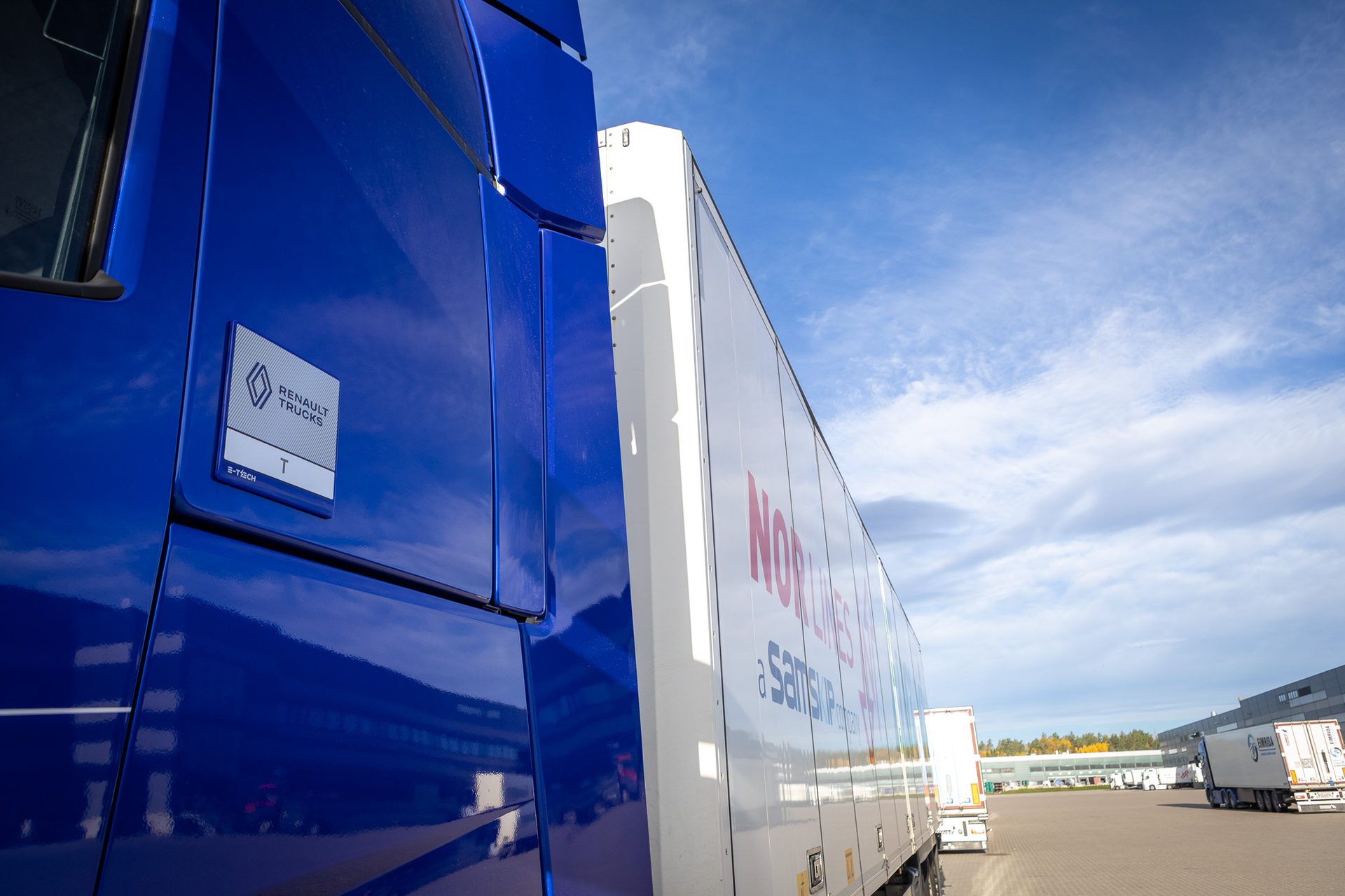 Blue Renault E-Tech T truck cab with white trailer under a partly cloudy sky.