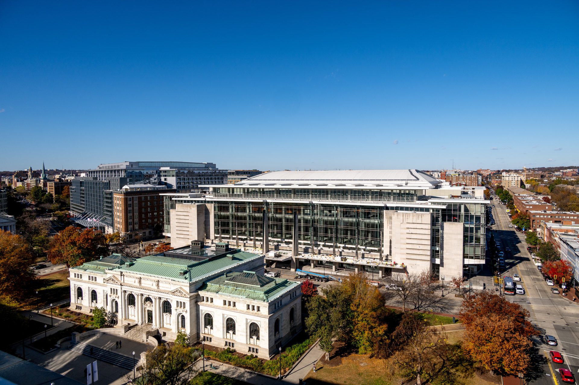 An aerial view of the historic Carnegie Library and a modern building amidst a vibrant autumn city.