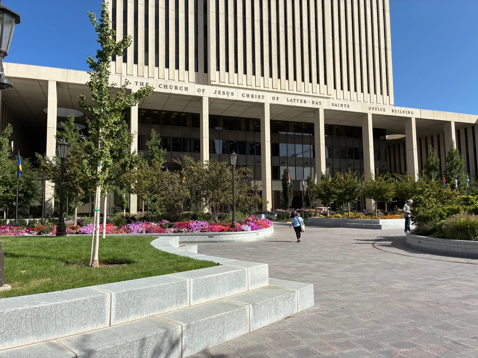 The Church of Jesus Christ of Latter-day Saints Office Building overlooks vibrant flower gardens and a busy plaza.