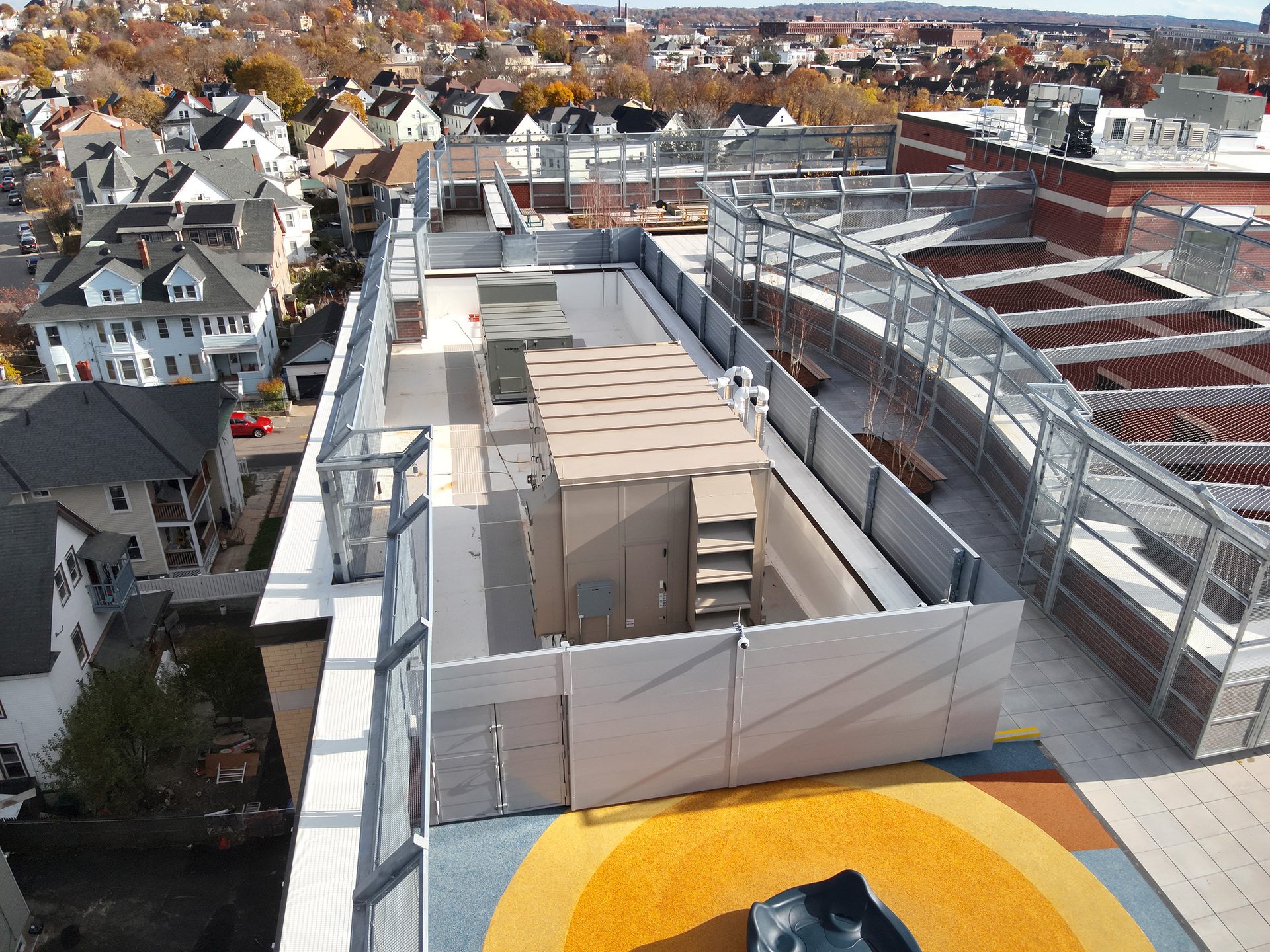 Rooftop deck with playground, structures, overlooking residential homes and city.