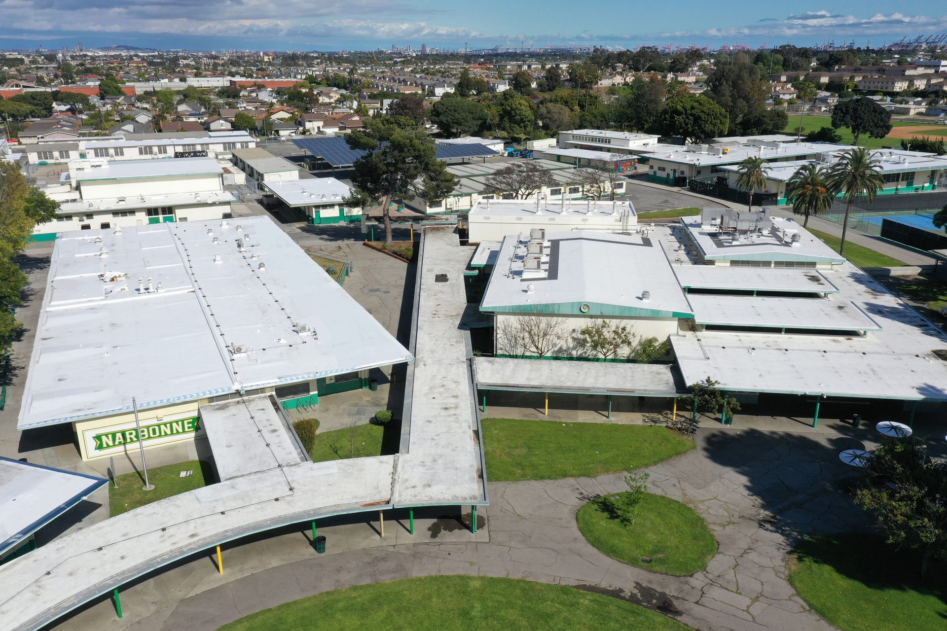 Aerial view of Narbonne High School campus, showing multiple white-roofed buildings, walkways, and solar panels.