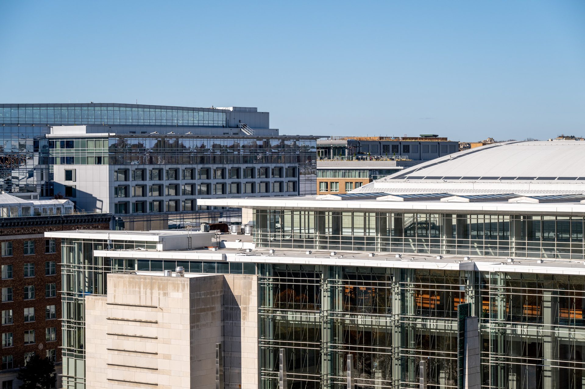 Panoramic view of a modern cityscape with various architectural styles, including glass, brick, and concrete buildings.