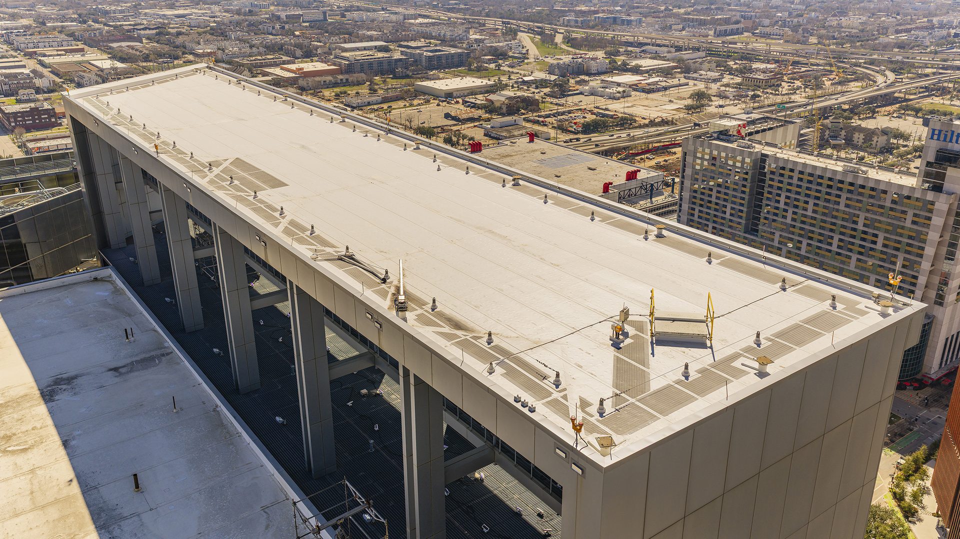 Aerial view of a long building's rooftop with equipment, overlooking a city skyline.