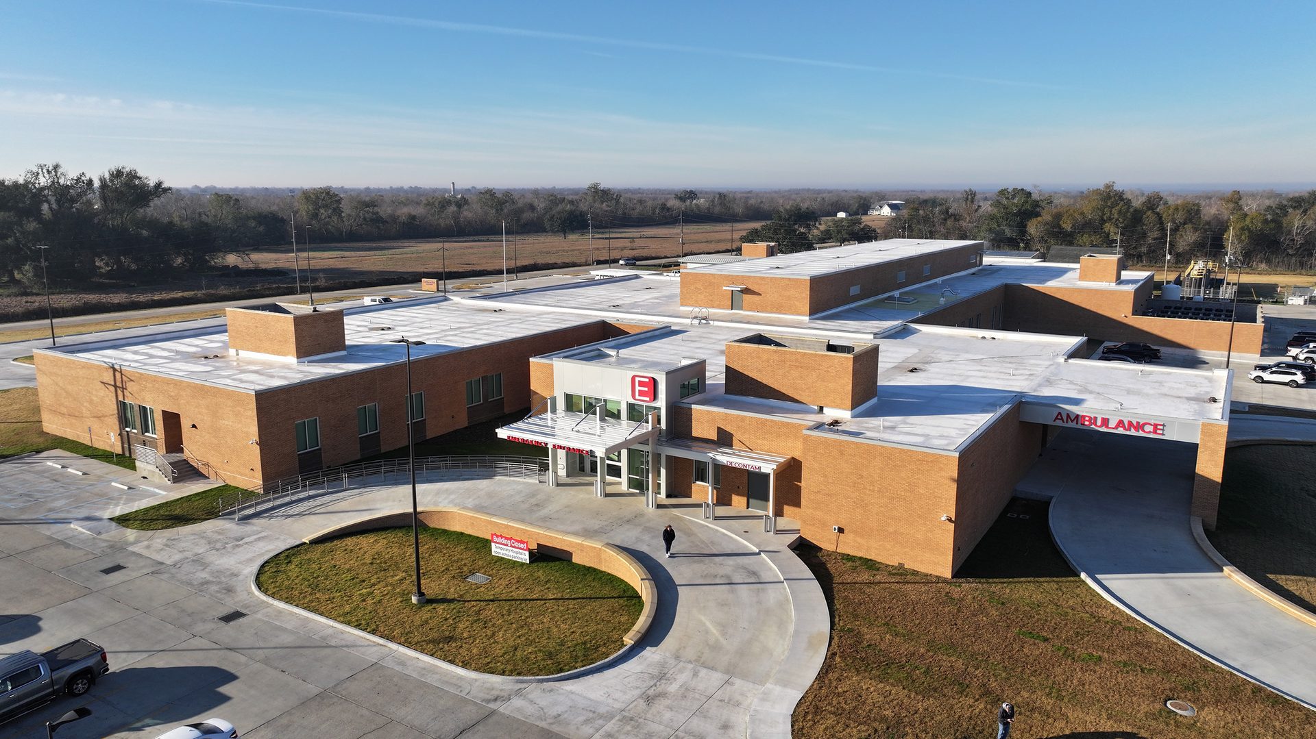 Aerial view of a modern brick emergency medical facility with clear emergency and ambulance entrances.