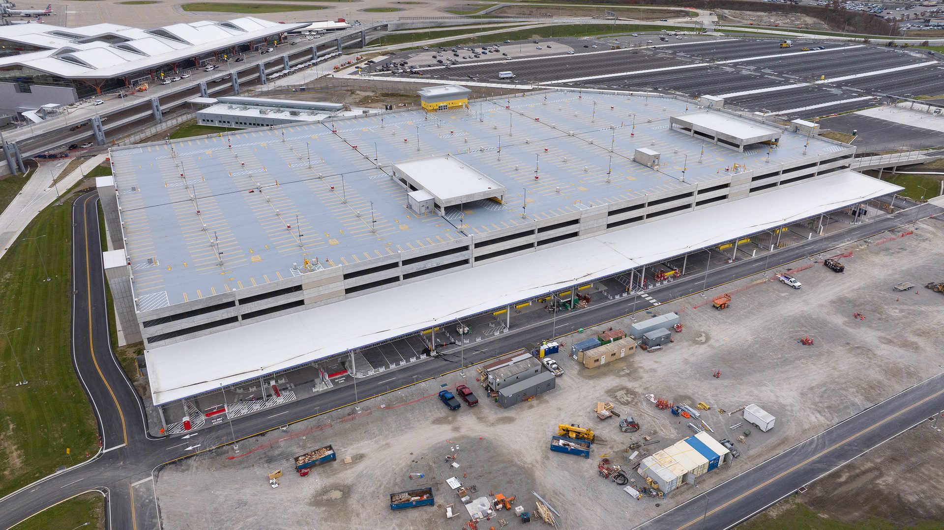 Aerial view of airport parking structure and terminal building with construction site in foreground.