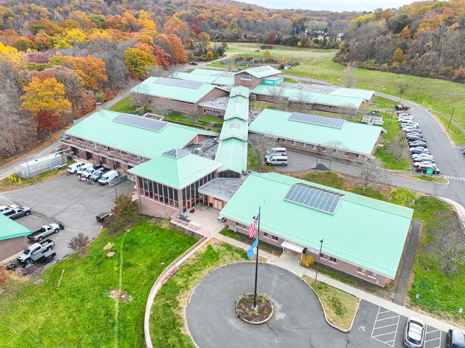 Aerial view of a sprawling building complex featuring green roofs, solar panels, and autumn trees.