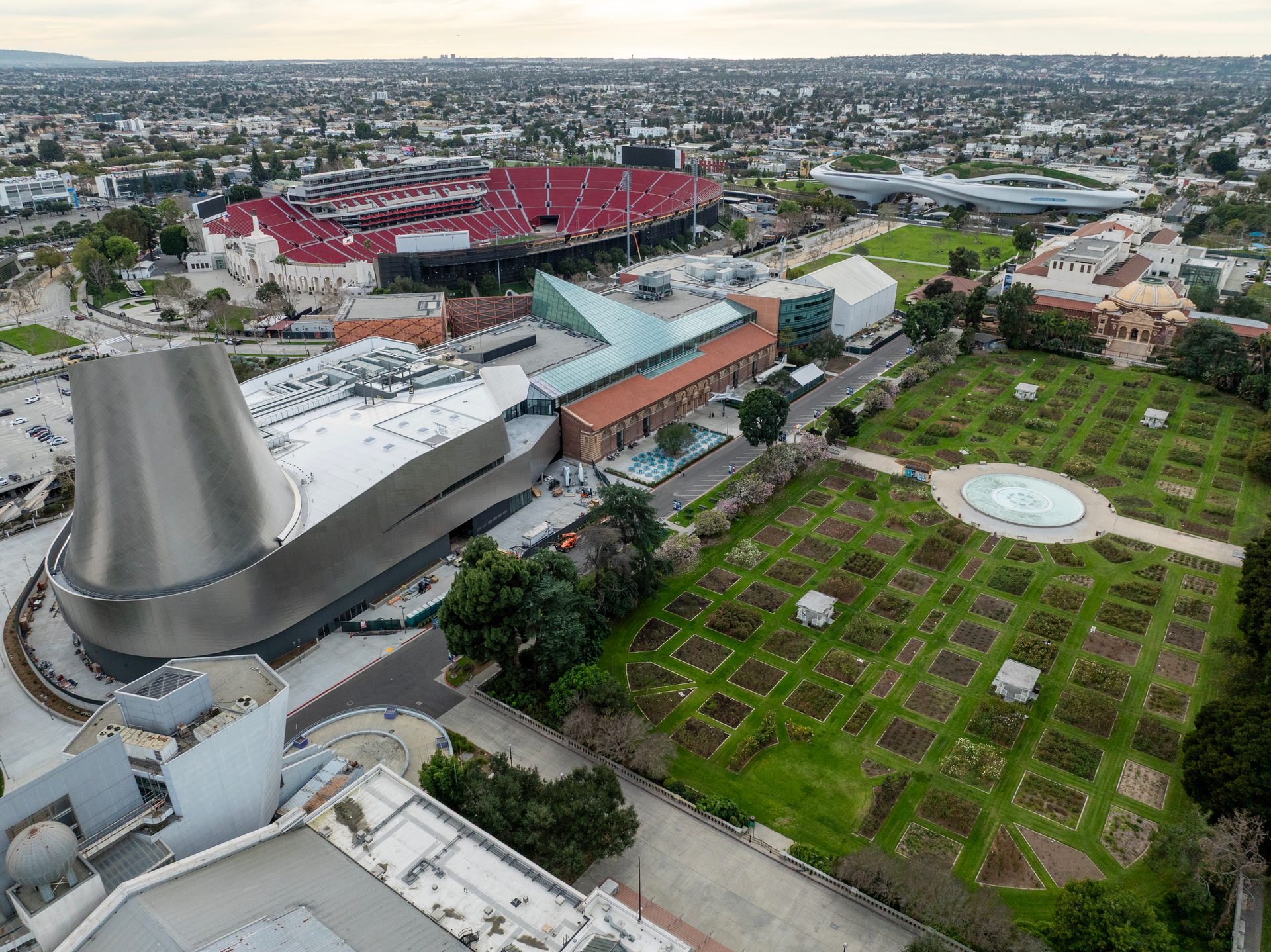 Aerial view of Exposition Park with Science Center, Coliseum, Lucas Museum, and Rose Garden.