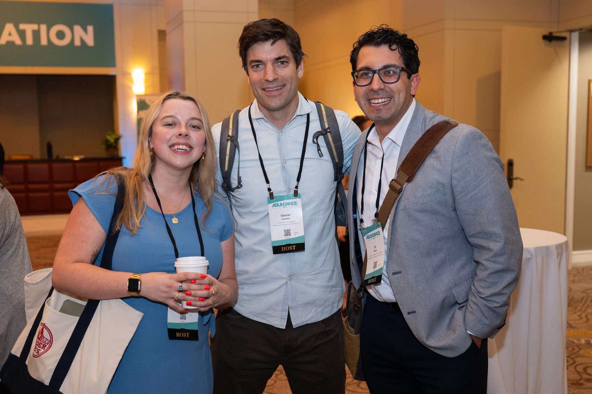 Three smiling people, including two hosts, at the Abundance conference.