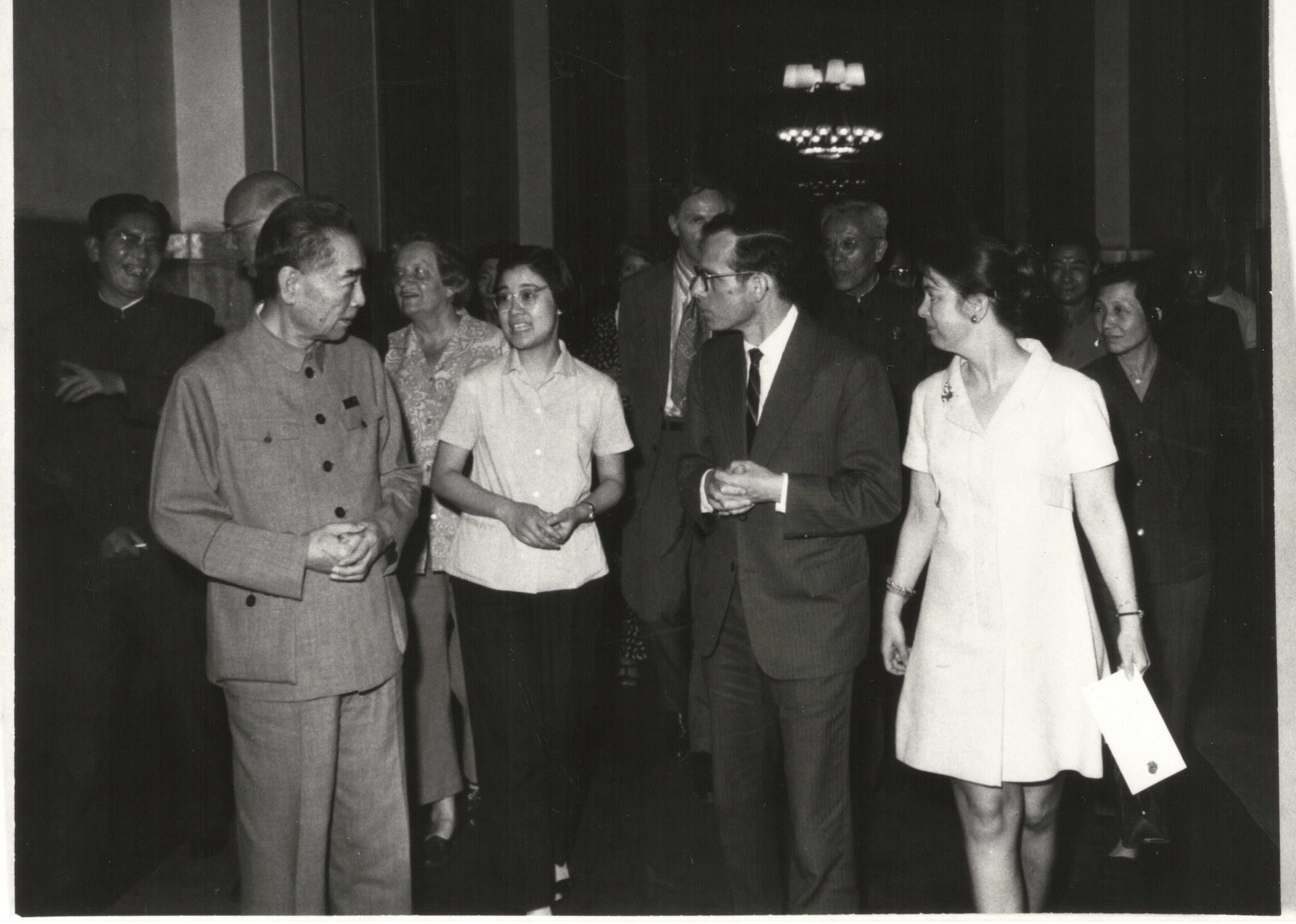 Premier Zhou Enlai in a Mao suit, conversing with a group of people, including women, indoors.
