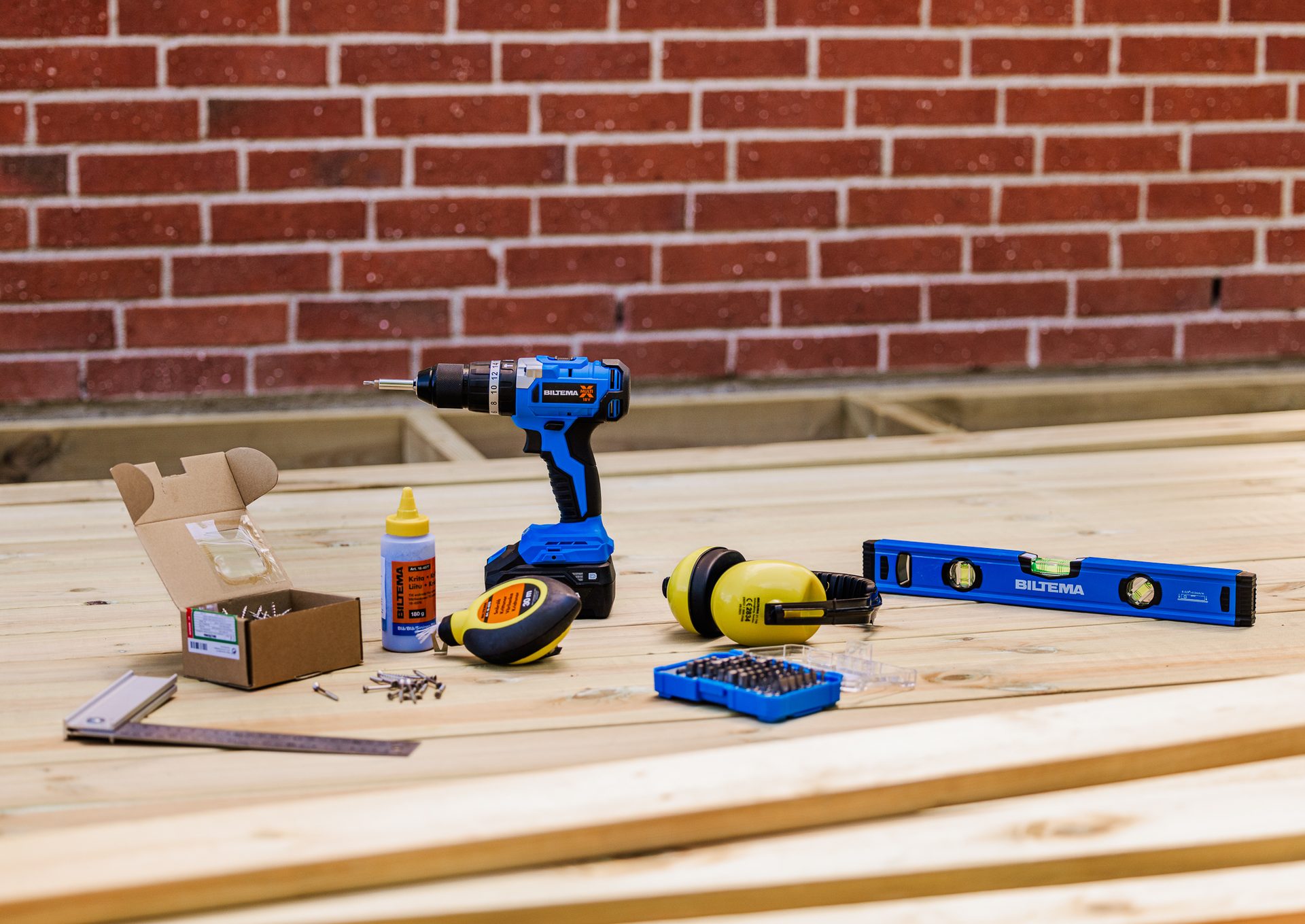 A collection of construction and woodworking tools on a wooden surface.