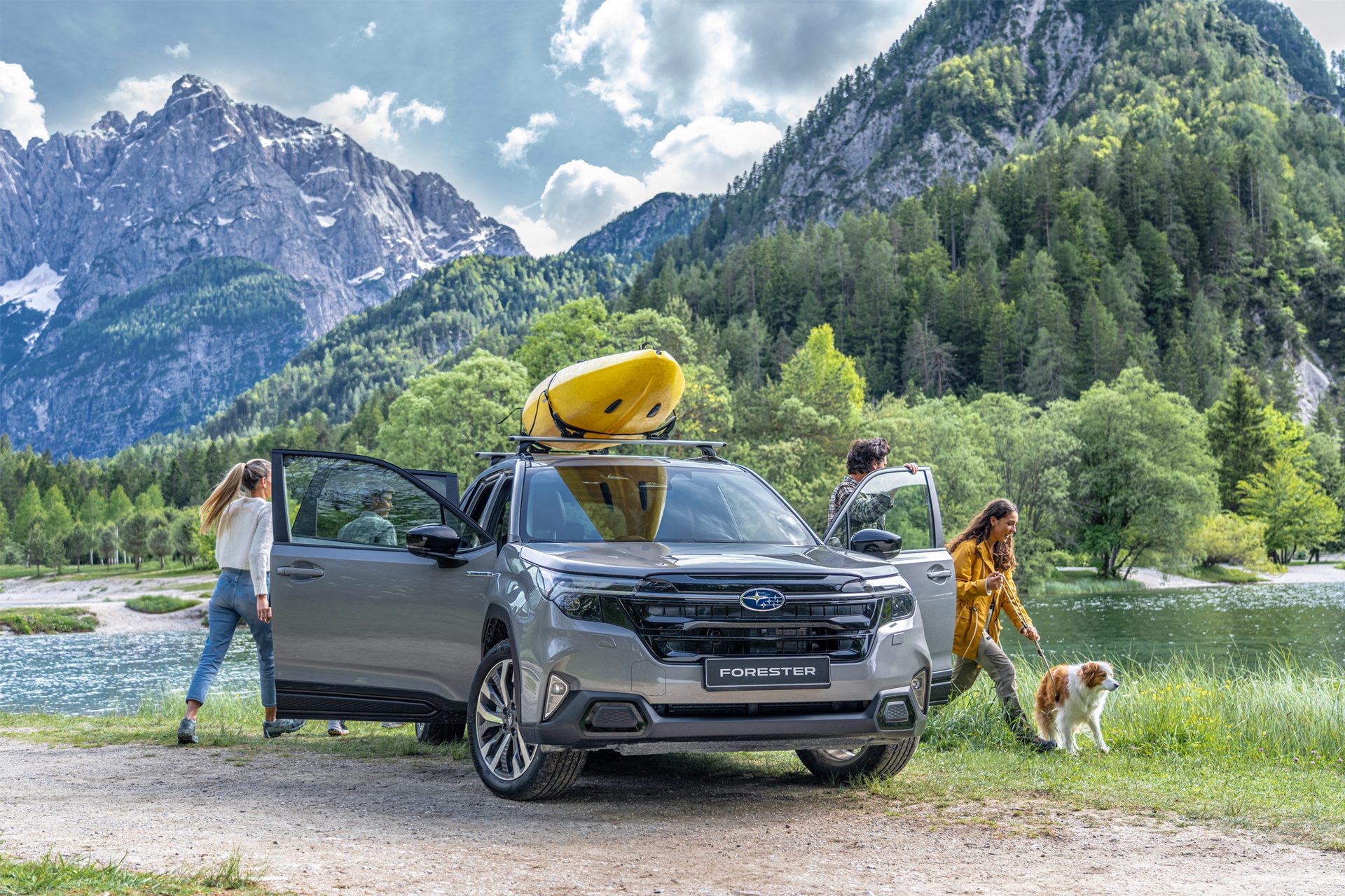 Subaru Forester with kayak, people, and dog at a lake in the mountains.