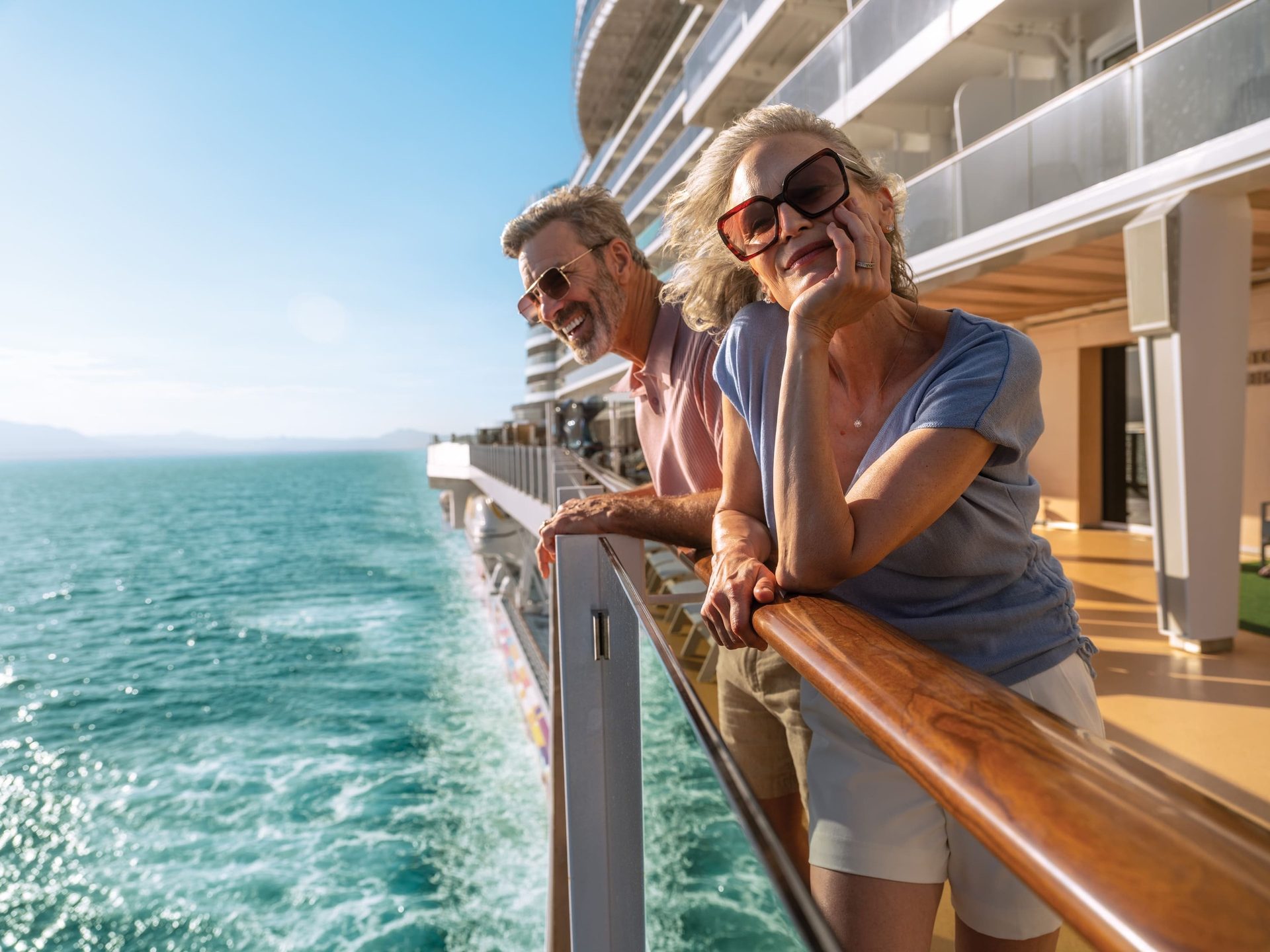 Happy senior couple enjoying ocean views from cruise ship balcony.