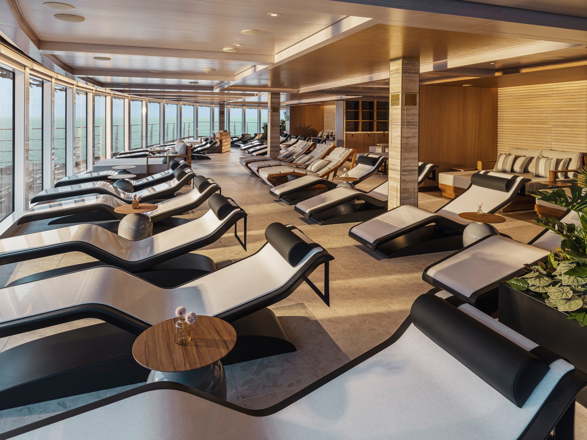 Luxury cruise ship lounge with modern recliners, panoramic ocean view, and comfortable seating for relaxation.