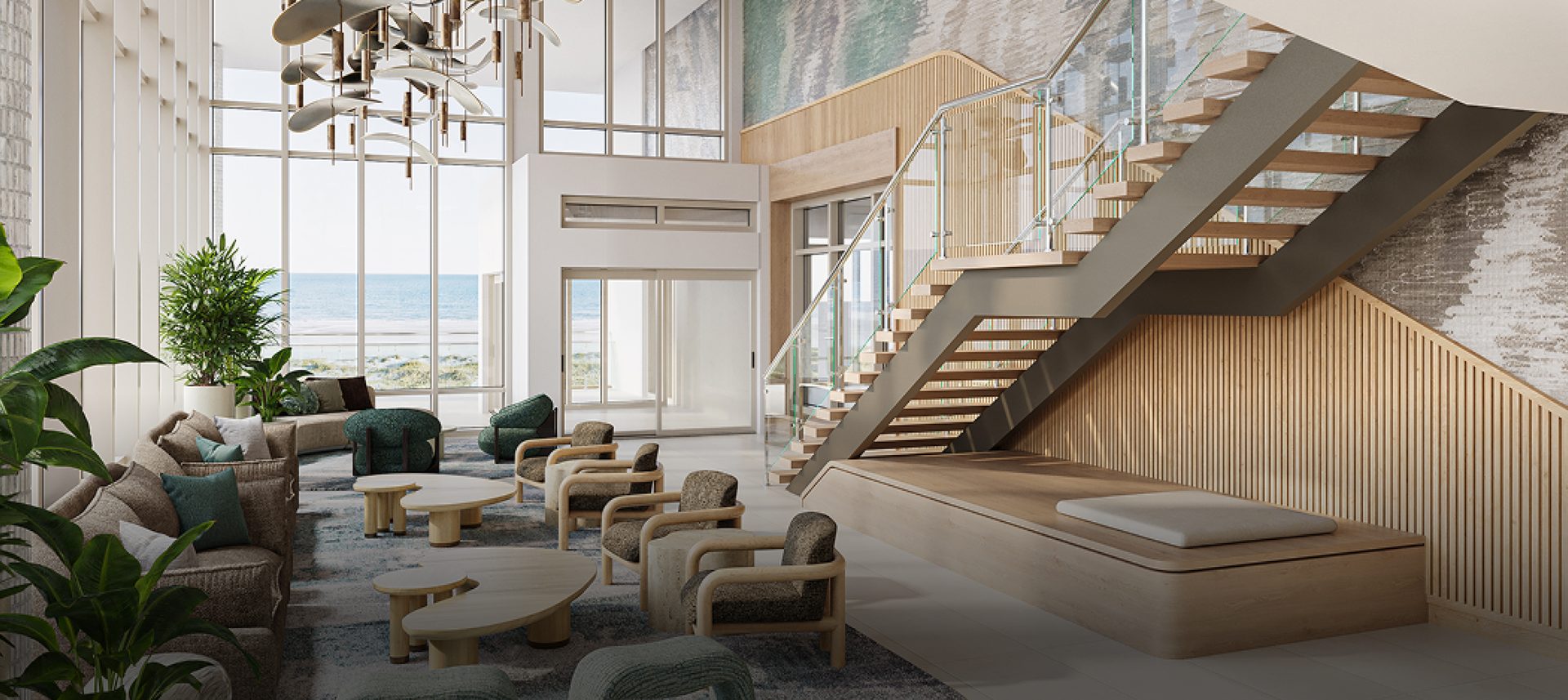 Modern hotel lobby with ocean view, comfy lounge, striking staircase, and high ceilings.