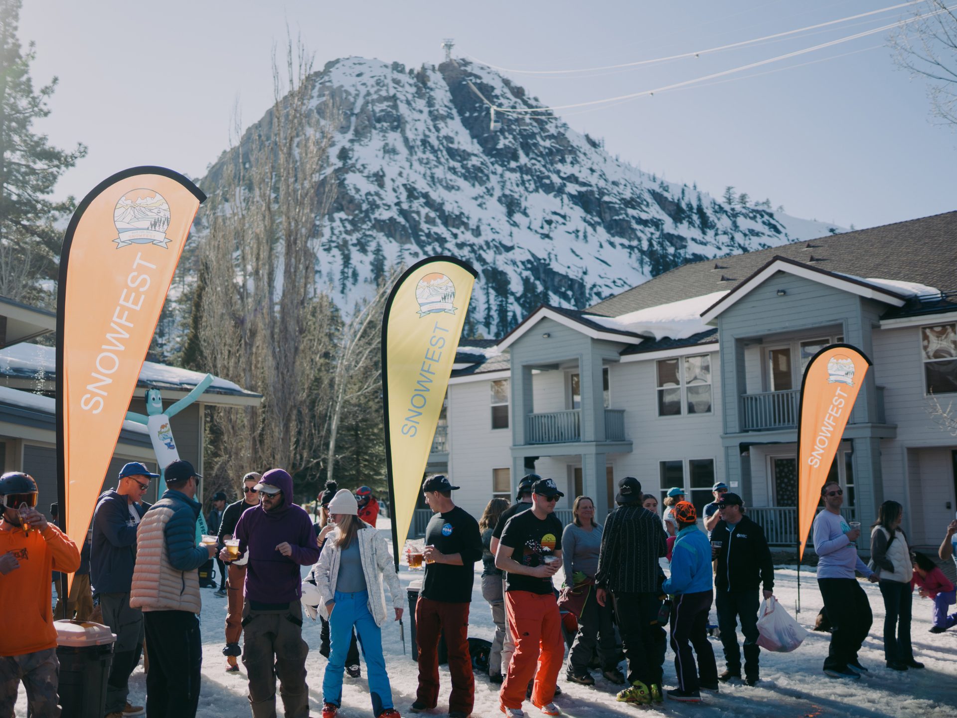 Outdoor Snowfest event with people drinking in the snow, set against a snowy mountain backdrop.