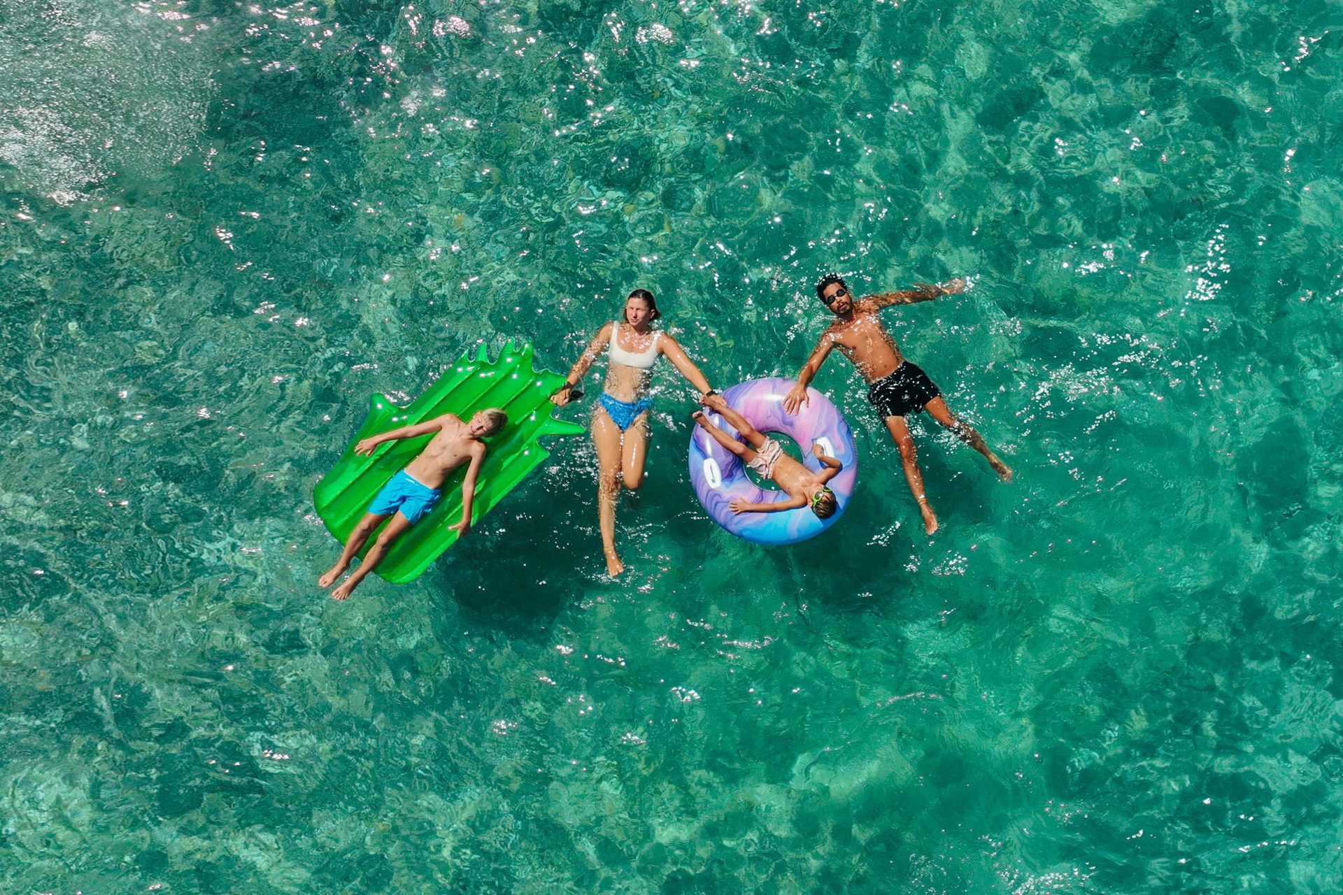 Family floats on rafts in clear water.