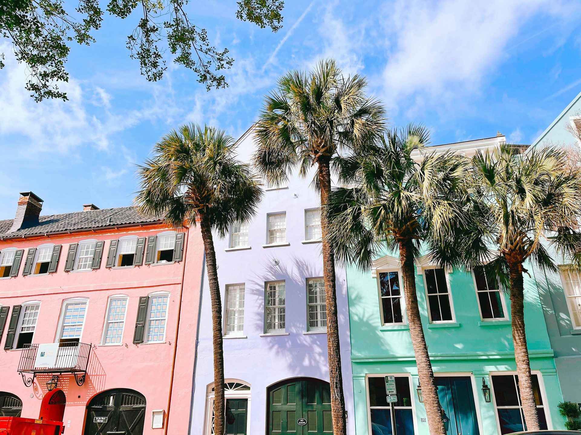 Colorful historic buildings in pink, purple, and turquoise with palm trees.
