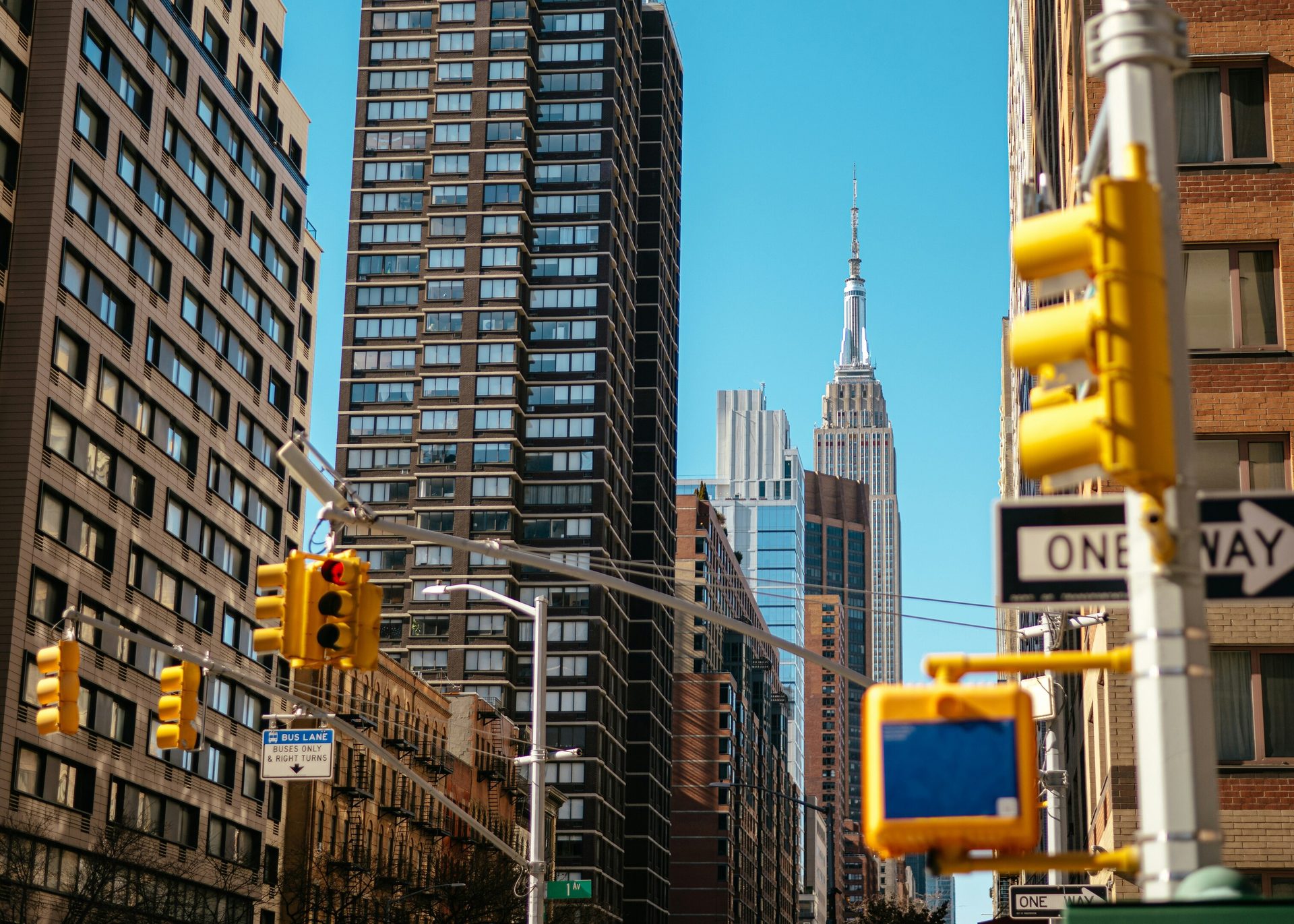 City street with tall buildings, traffic lights, and the Empire State Building.