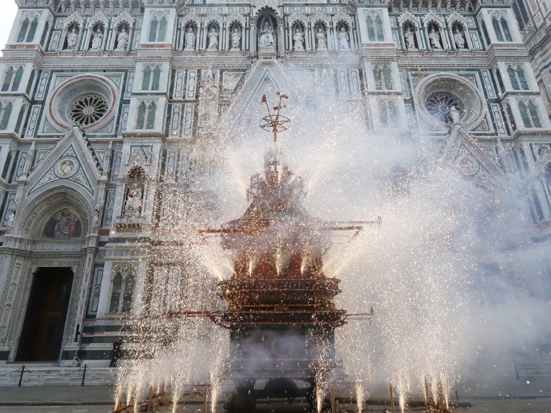 Fireworks erupt from a cart before the ornate Florence Duomo facade.