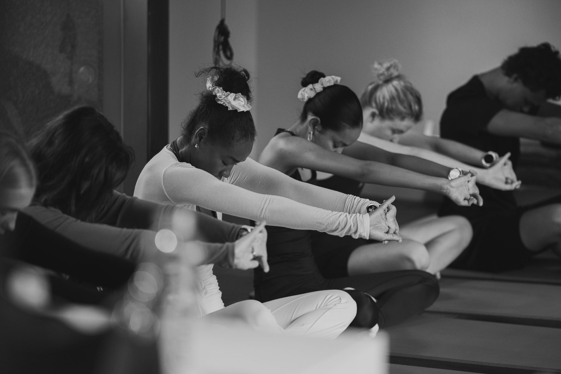 Black and white photo of people sitting and stretching arms forward in a row.