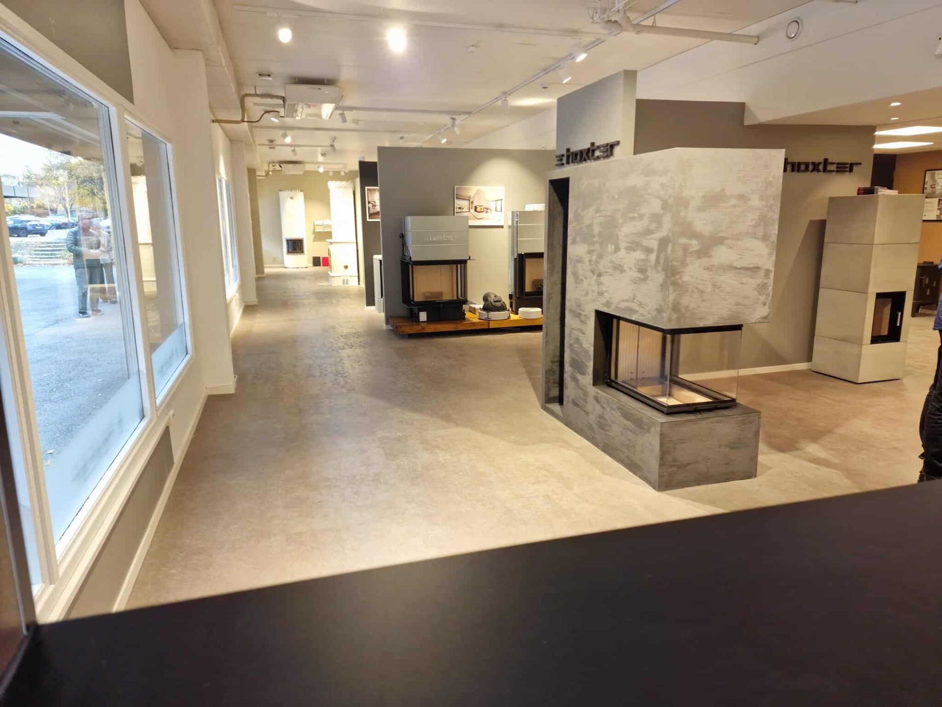 Modern fireplace showroom with various models, large windows, and contemporary design.