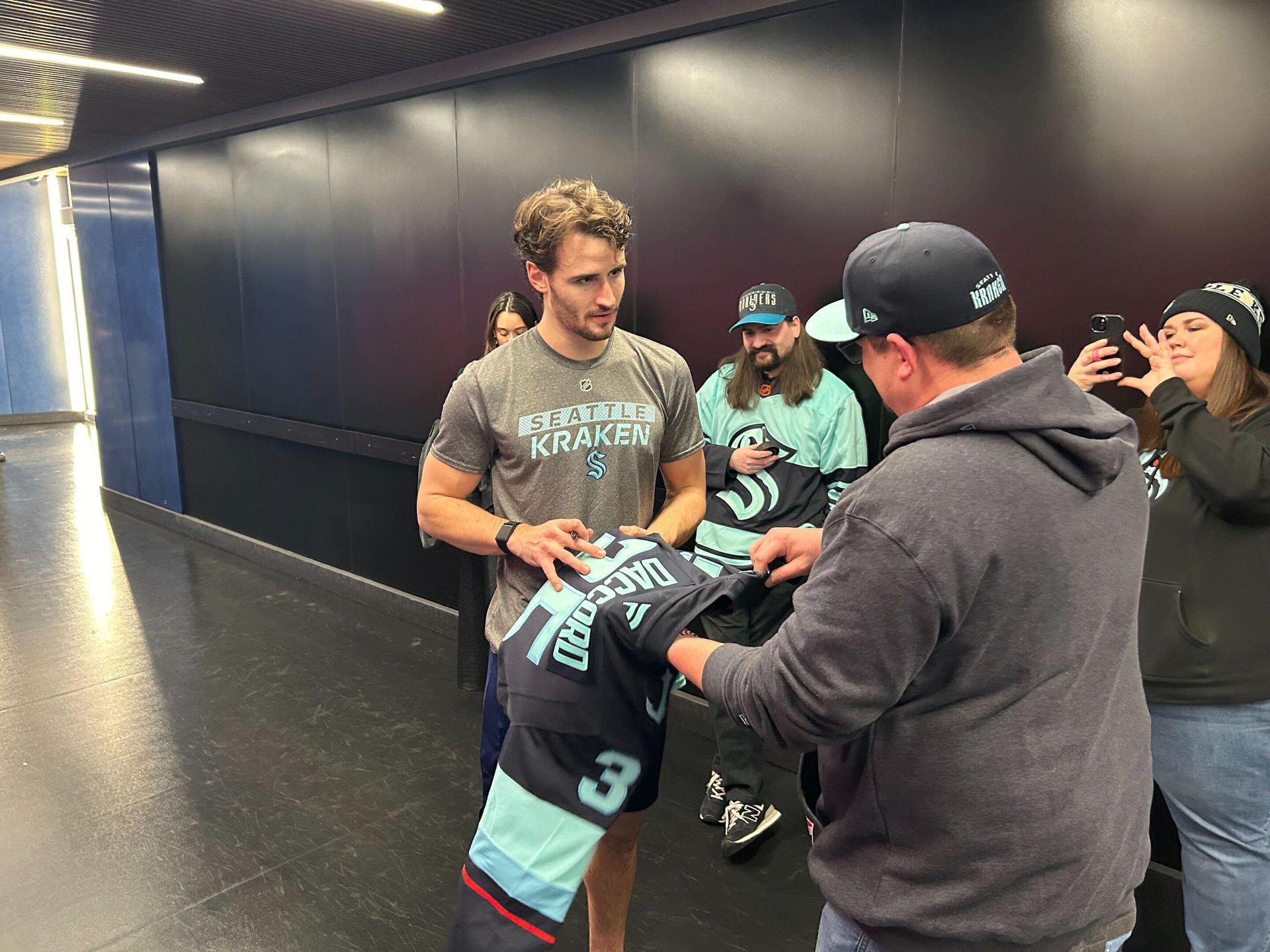 Seattle Kraken player signs jersey for fan.