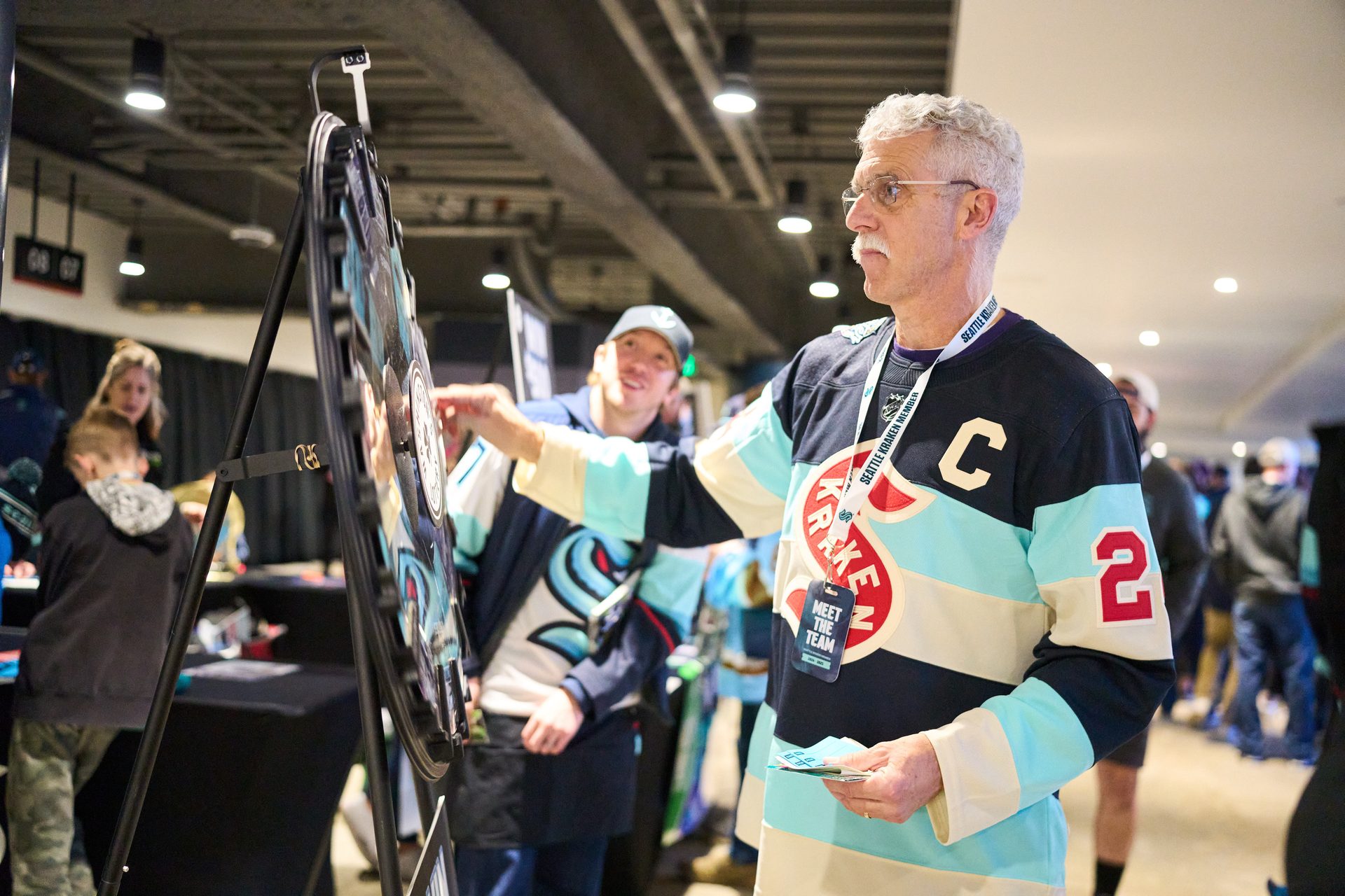 Man in Seattle Kraken jersey spins a prize wheel at a team event.