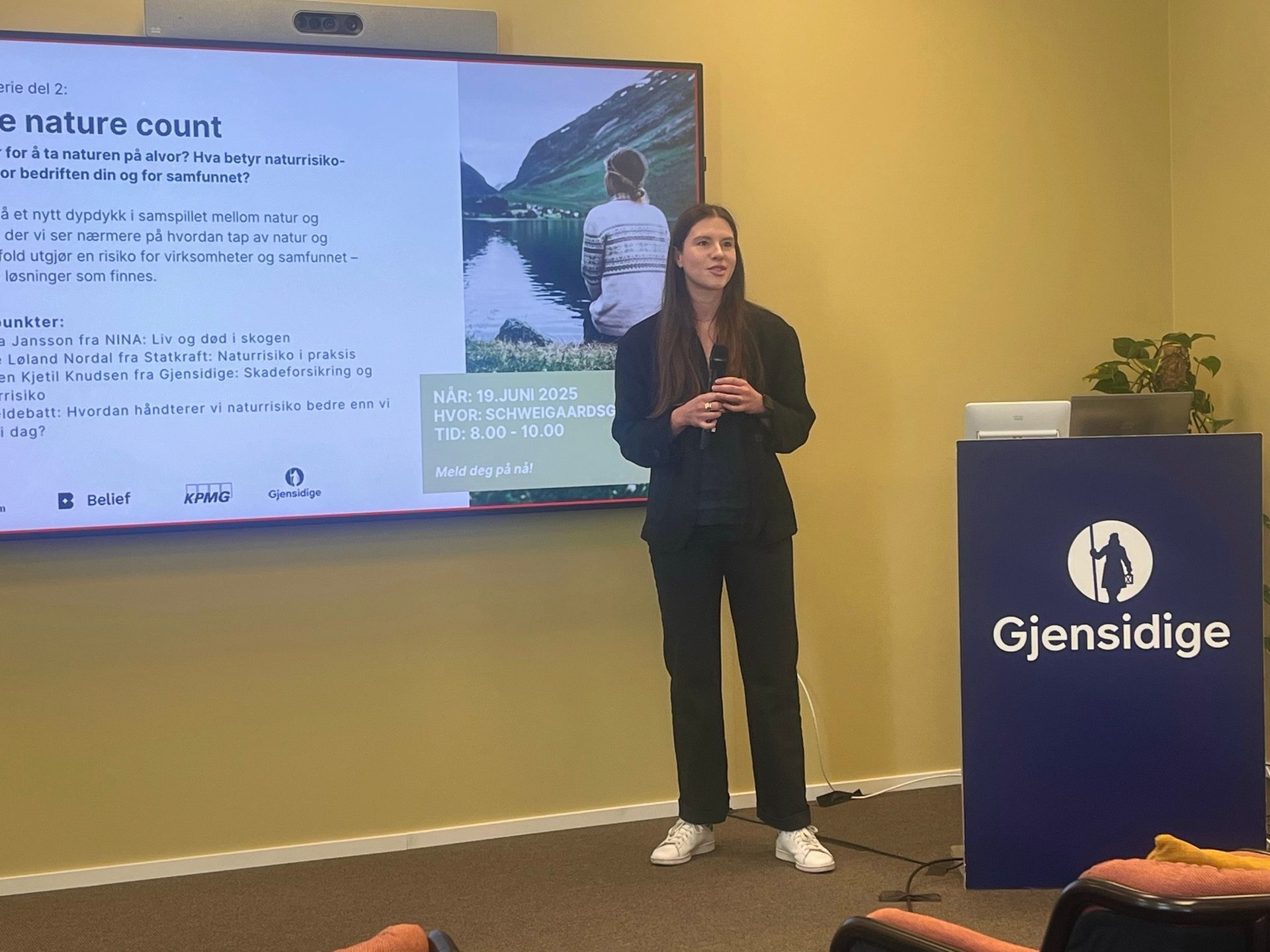 Woman presents on nature risk. Screen shows event details, Gjensidige, KPMG, Belief logos.