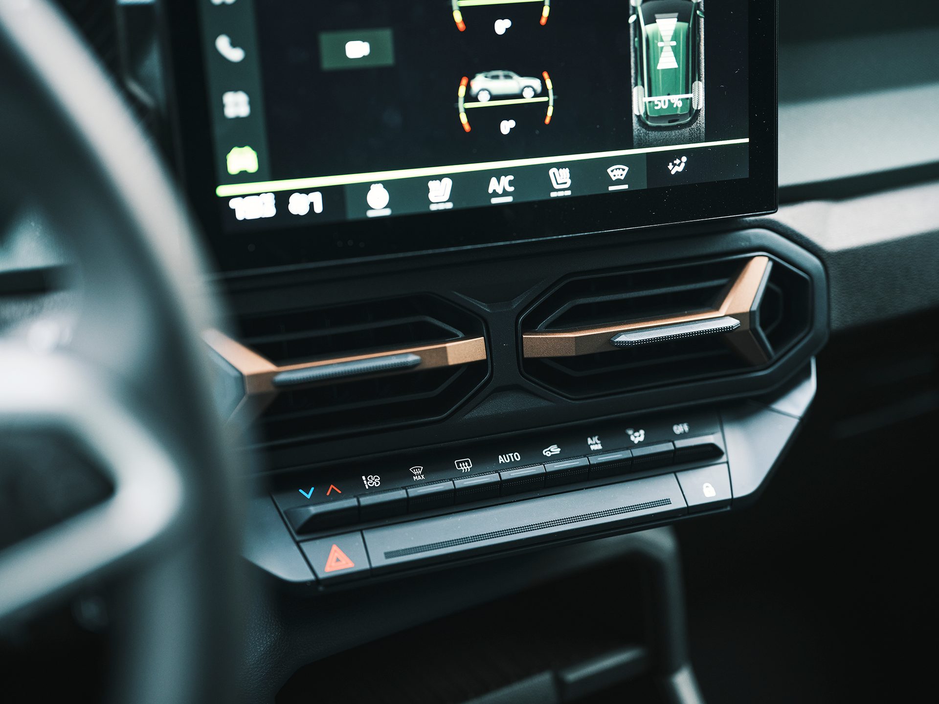 Modern car interior with infotainment screen, climate controls, and unique bronze-accented air vents.