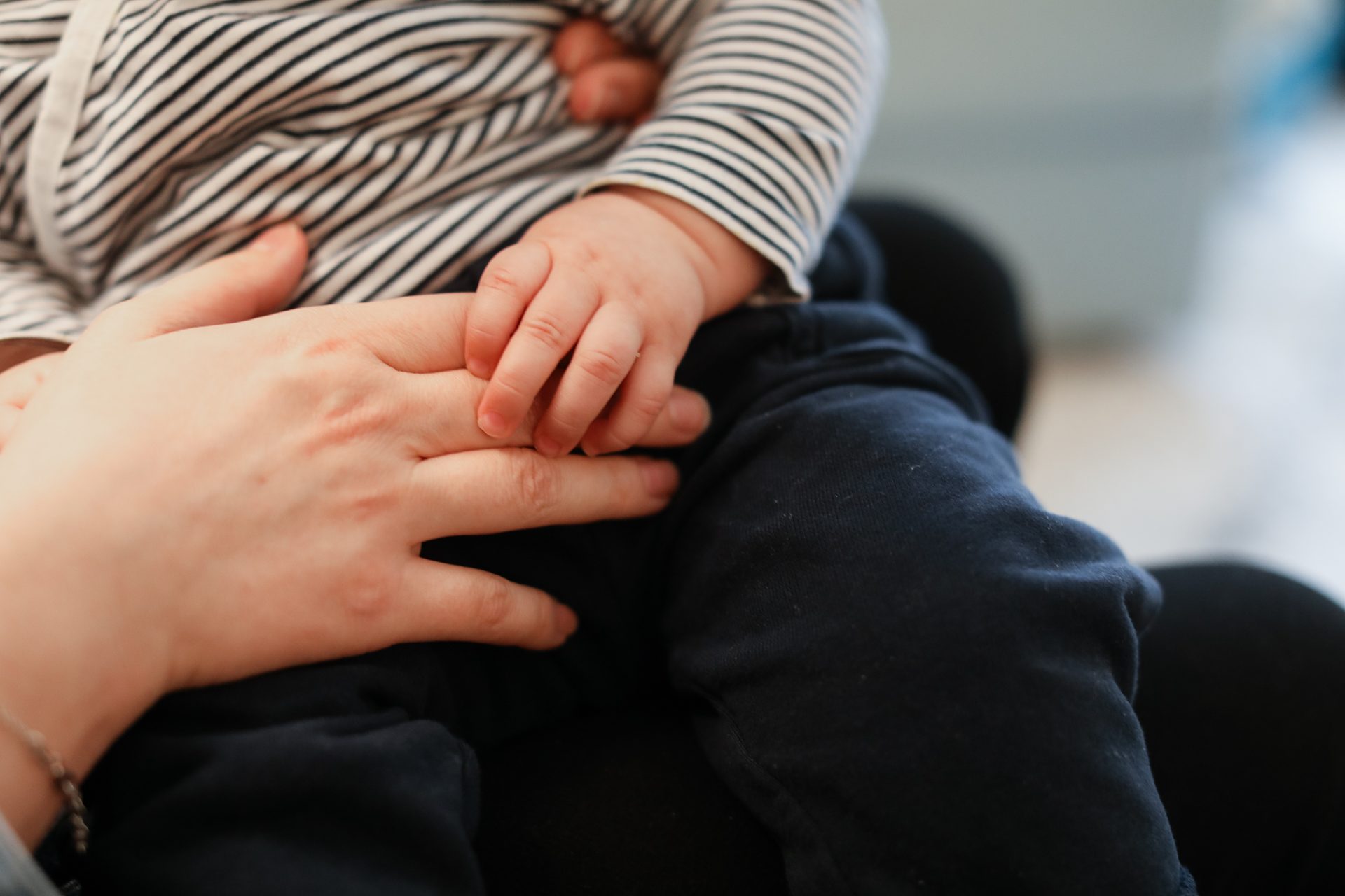 Baby's small hand gently holding an adult's hand, symbolizing a tender bond.