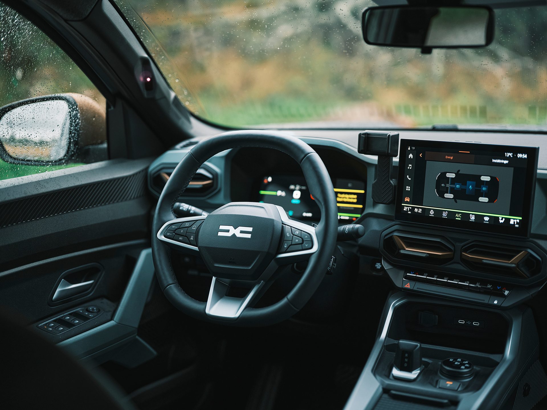 Interior view of a modern car with a Dacia steering wheel, digital infotainment screen, and detailed dashboard.