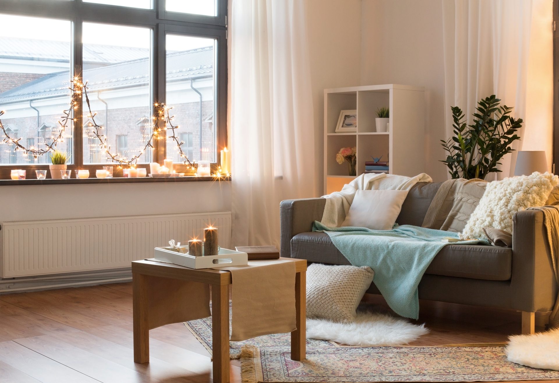Cozy living room with warm ambiance, featuring string lights, candles, a sofa, and a coffee table.